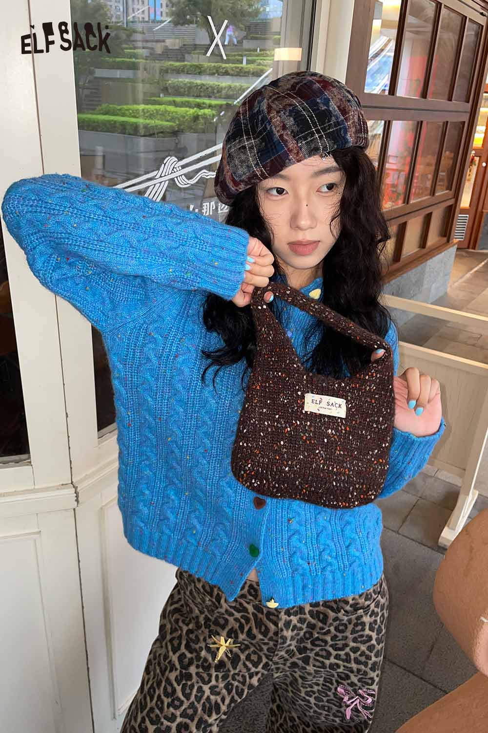 ELFSACK color block handwoven tote bag held by a model in a blue sweater and patterned pants