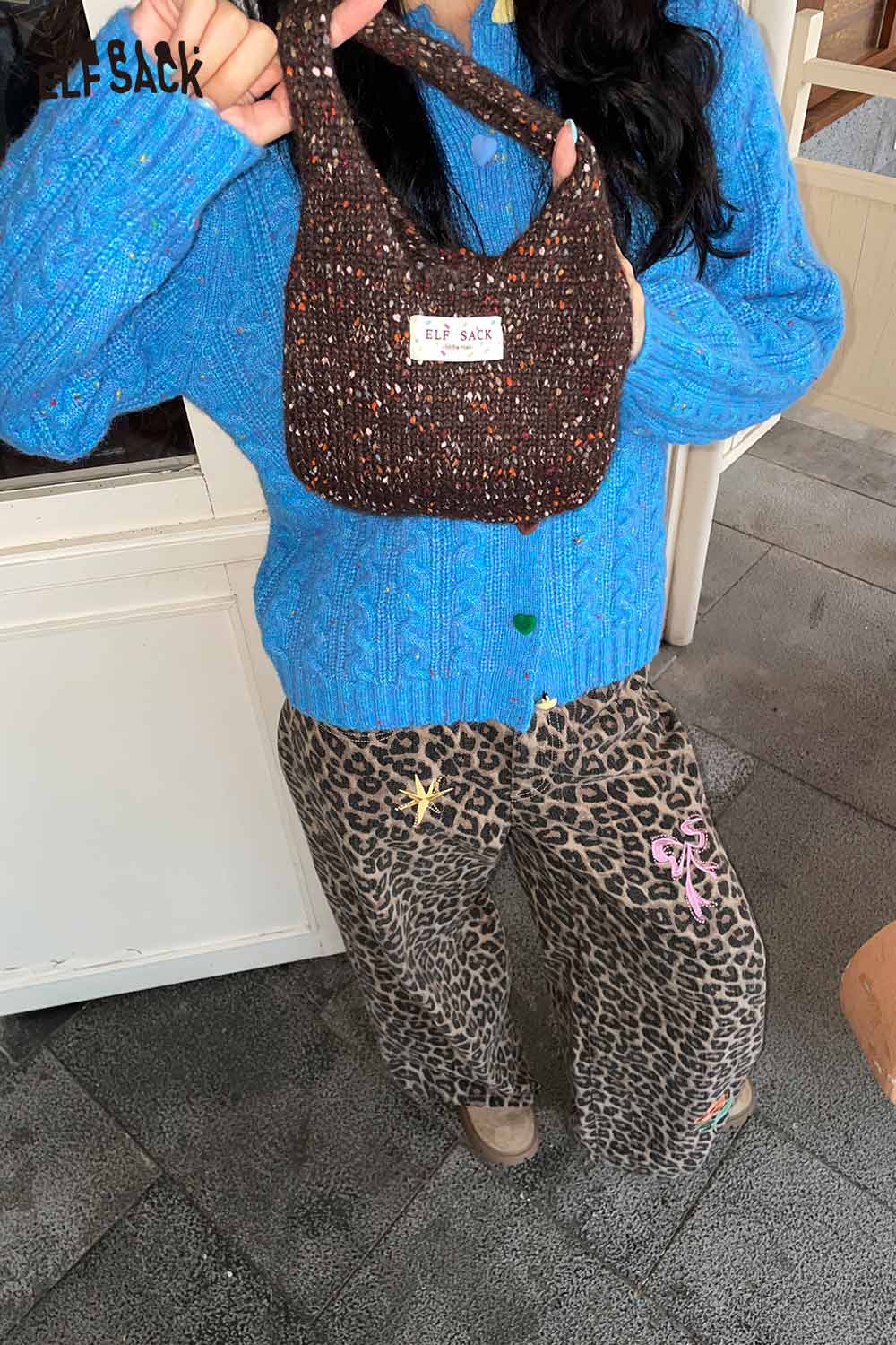 ELFSACK color block handwoven tote bag held by a model in a blue sweater and patterned pants