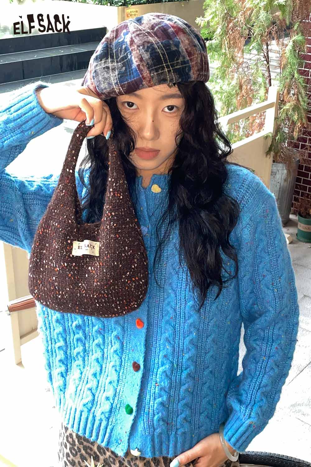 Stylish model holding a color block handwoven tote bag with a vibrant blue sweater from ELFSACK