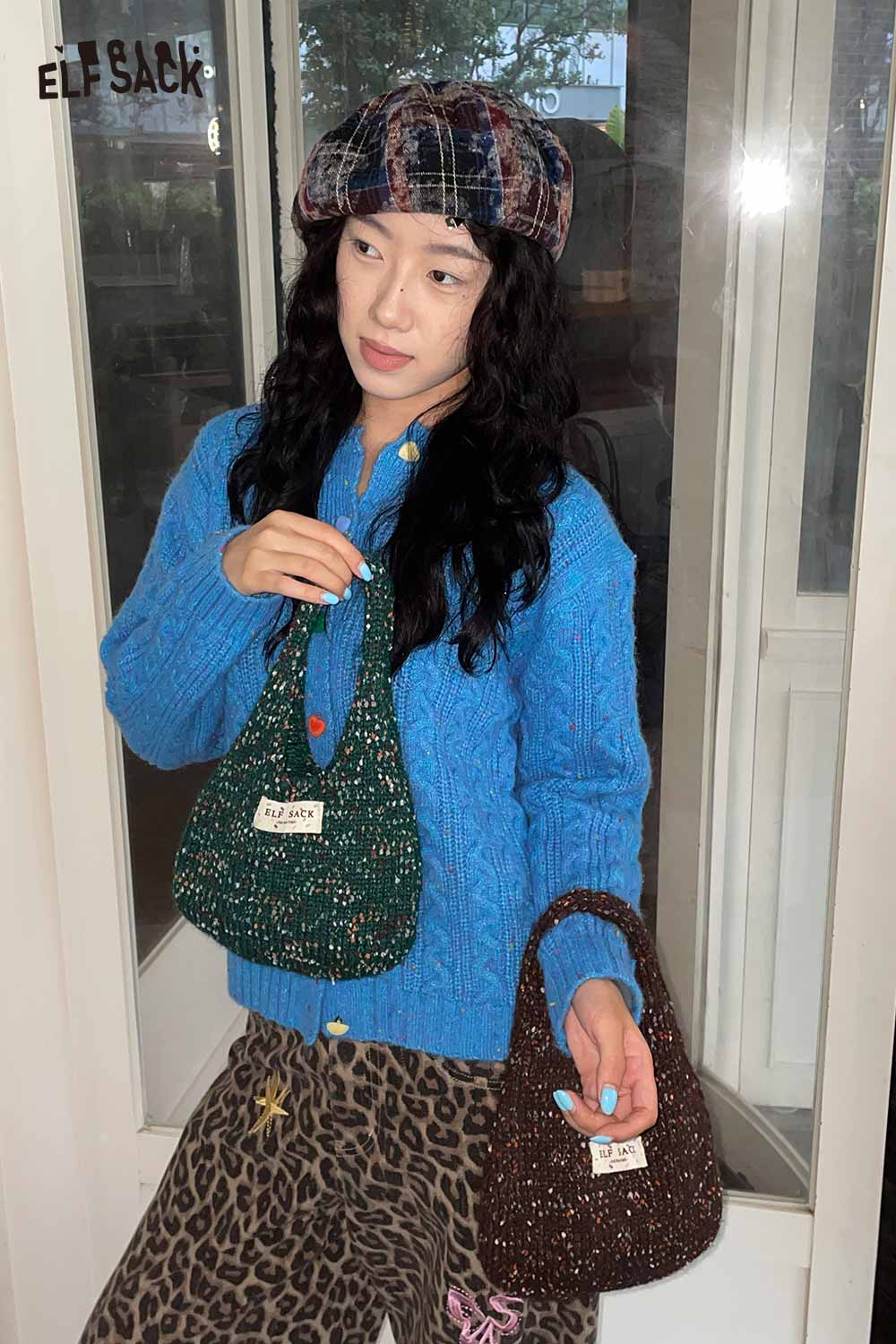 Woman wearing a blue cable knit sweater holding a color block handwoven tote bag in green and brown