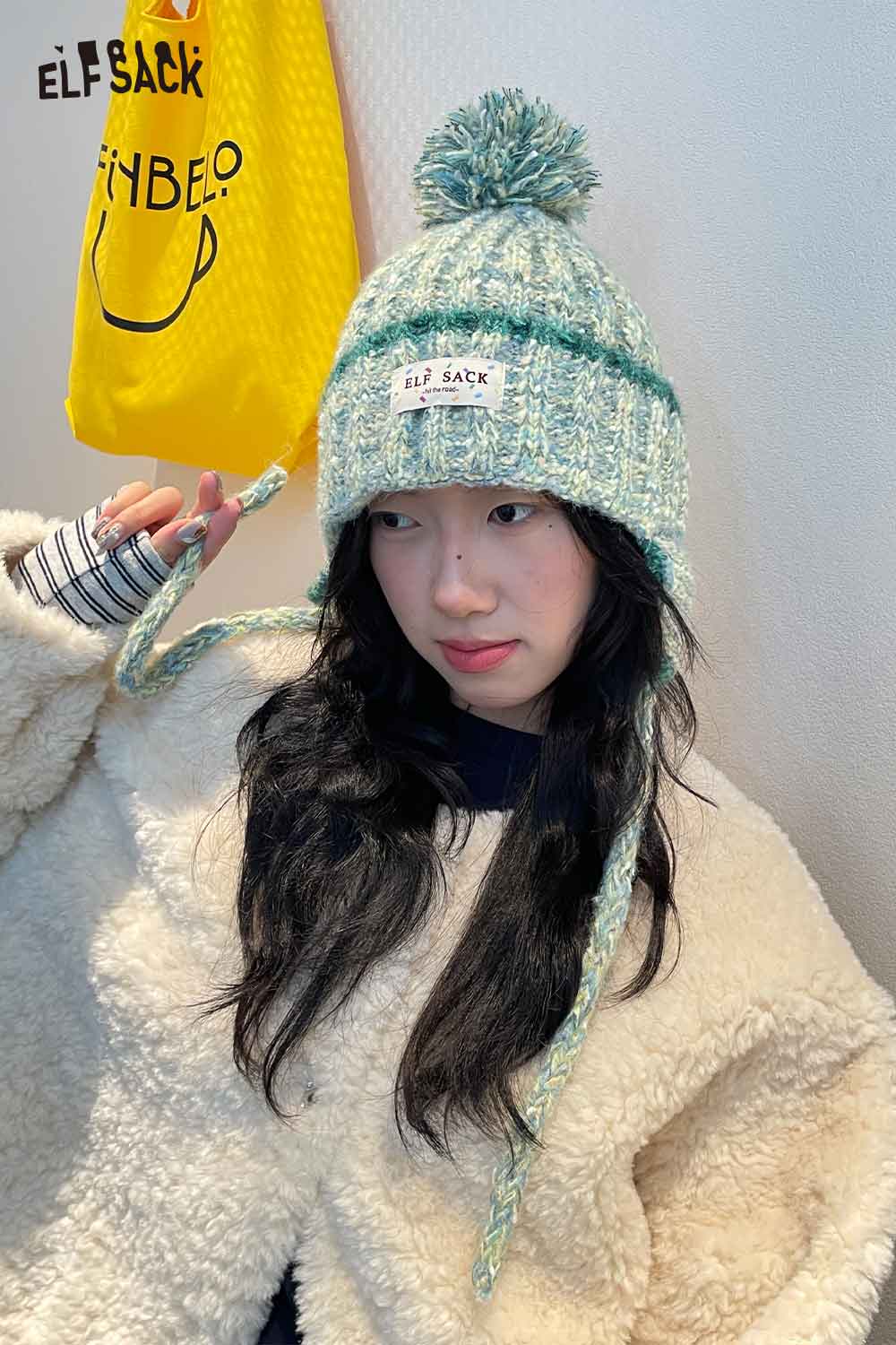 Cute striped pom beanie for women in soft teal with braided ties and a fluffy pom pom on top