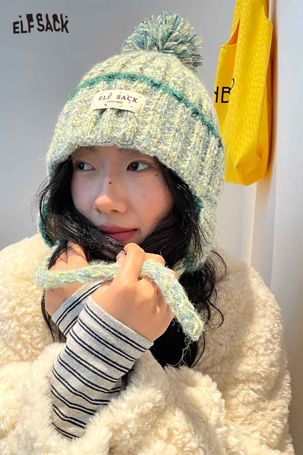 Cute striped pom beanie for women in pastel colors with a fluffy texture and ELFSACK logo