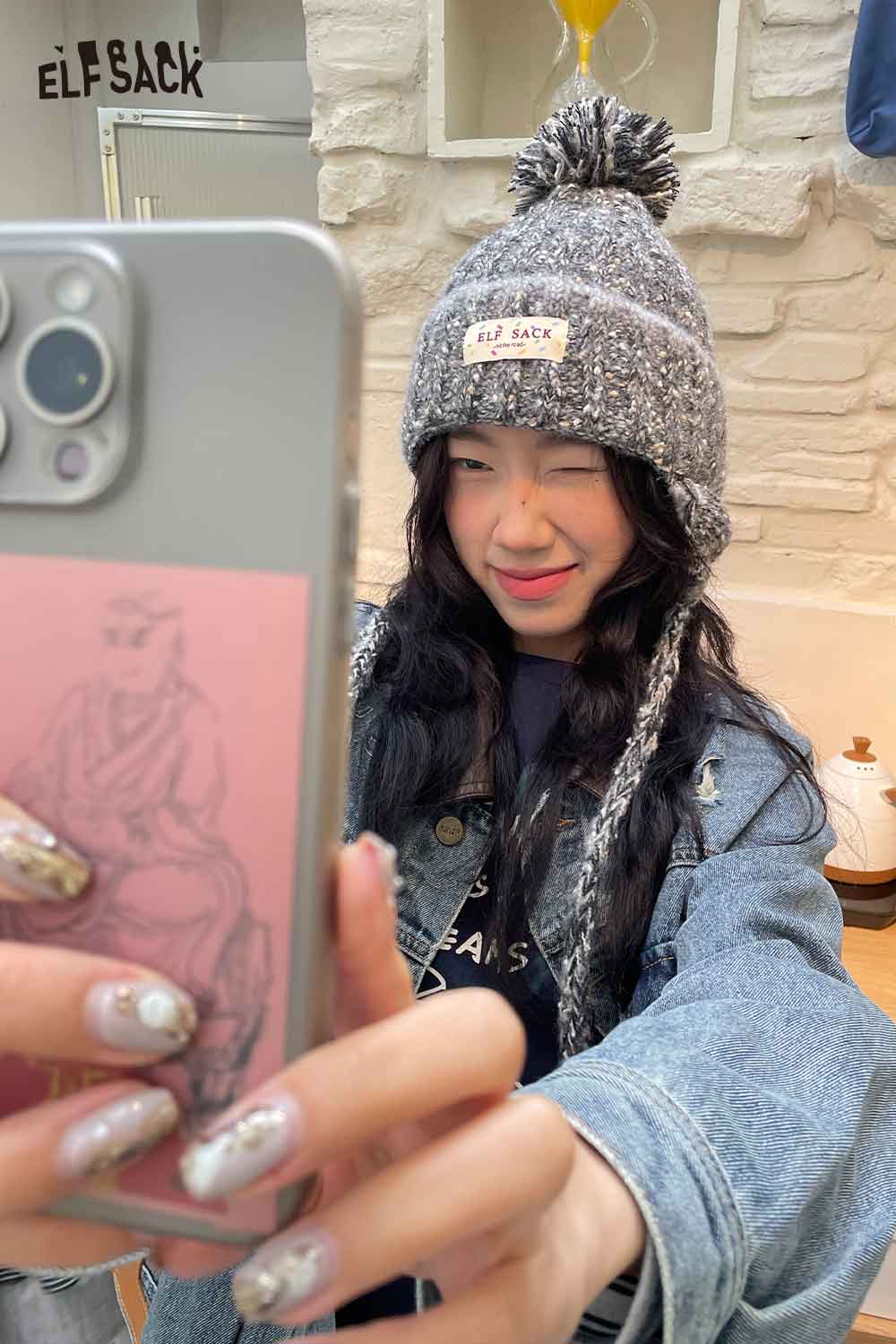 Cute striped pom beanie for women modeled by a girl with a playful expression in a cozy setting