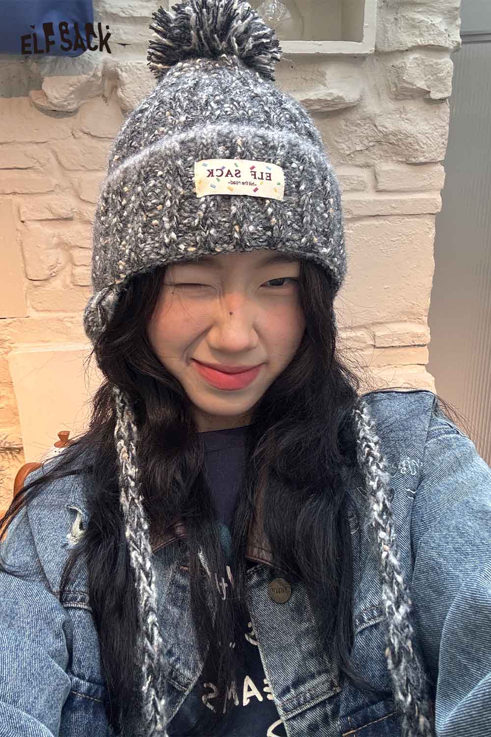 Cute striped pom beanie for women in gray with a logo tag for stylish winter wear