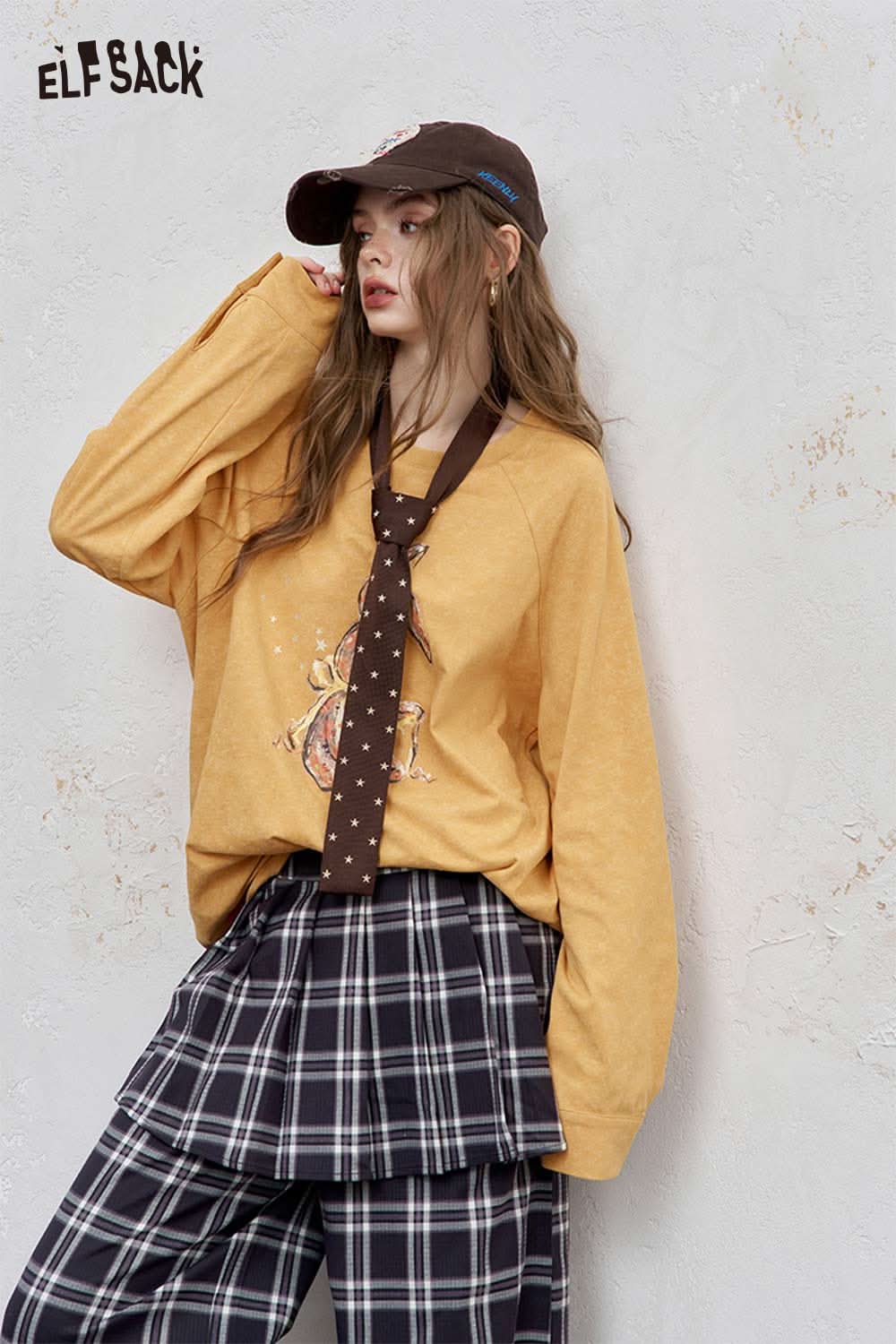 ELFSACK organic cotton embroidered long sleeve tee in yellow, styled with a plaid skirt and cap
