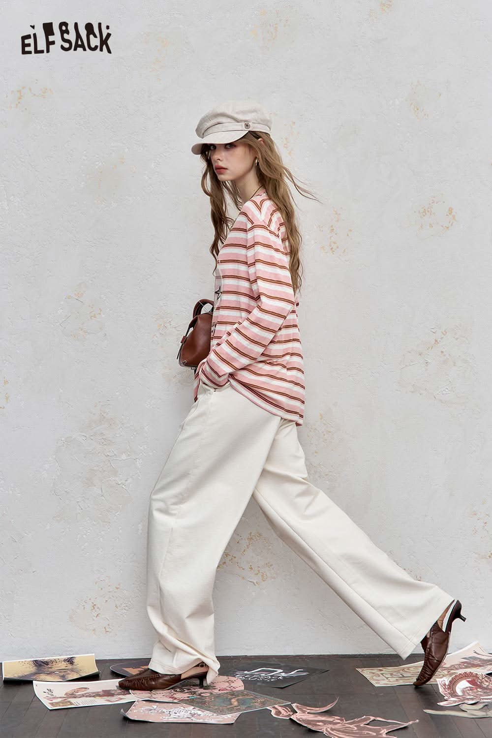 Model wearing a playful embroidered stripe shirt with beige and pink stripes paired with cream wide-leg pants