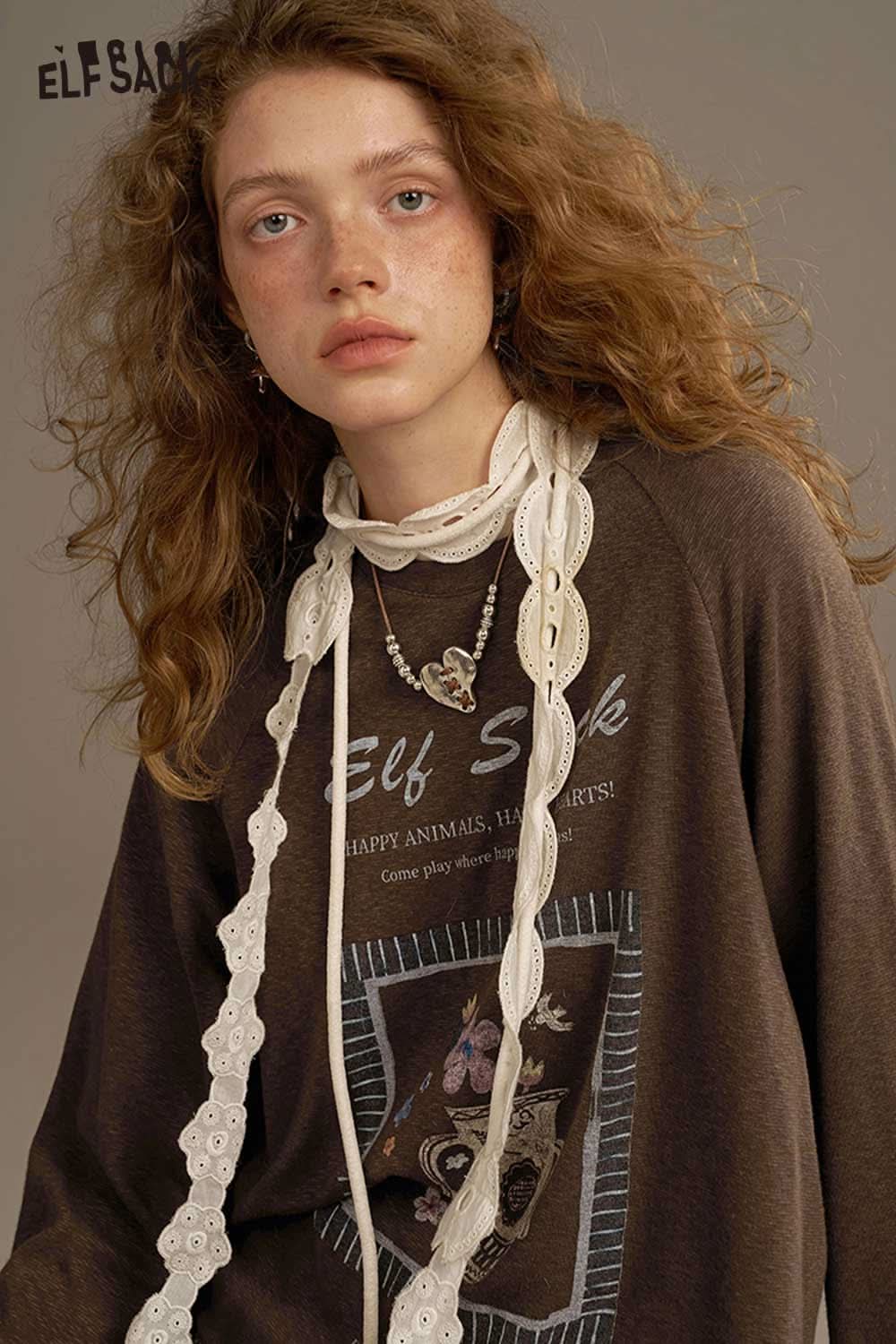 Model wearing ELFSACK soft printed raglan sleeve sweatshirt in dark gray with decorative accessories