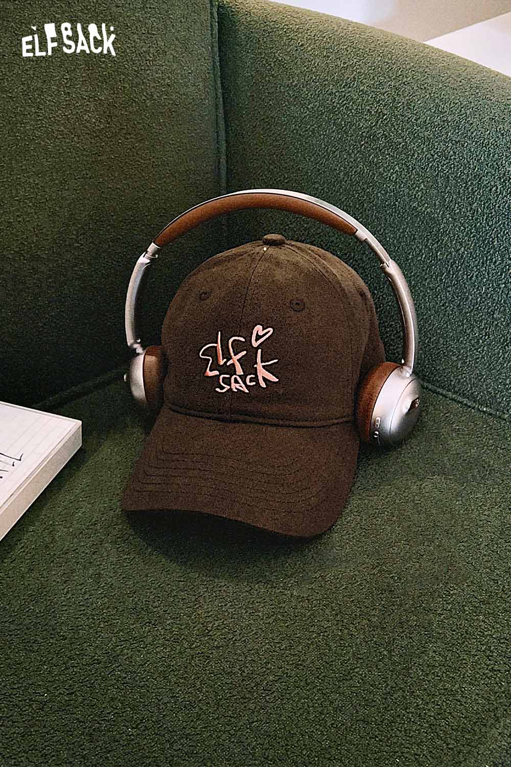 ELFSACK vintage embroidered baseball cap displayed on a green couch with headphones