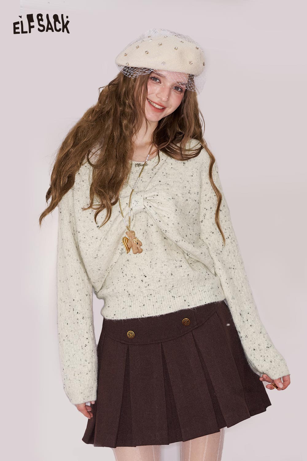 ELFSACK bow embellished cutout sweater in cream with a stylish twist detail, paired with a pleated skirt