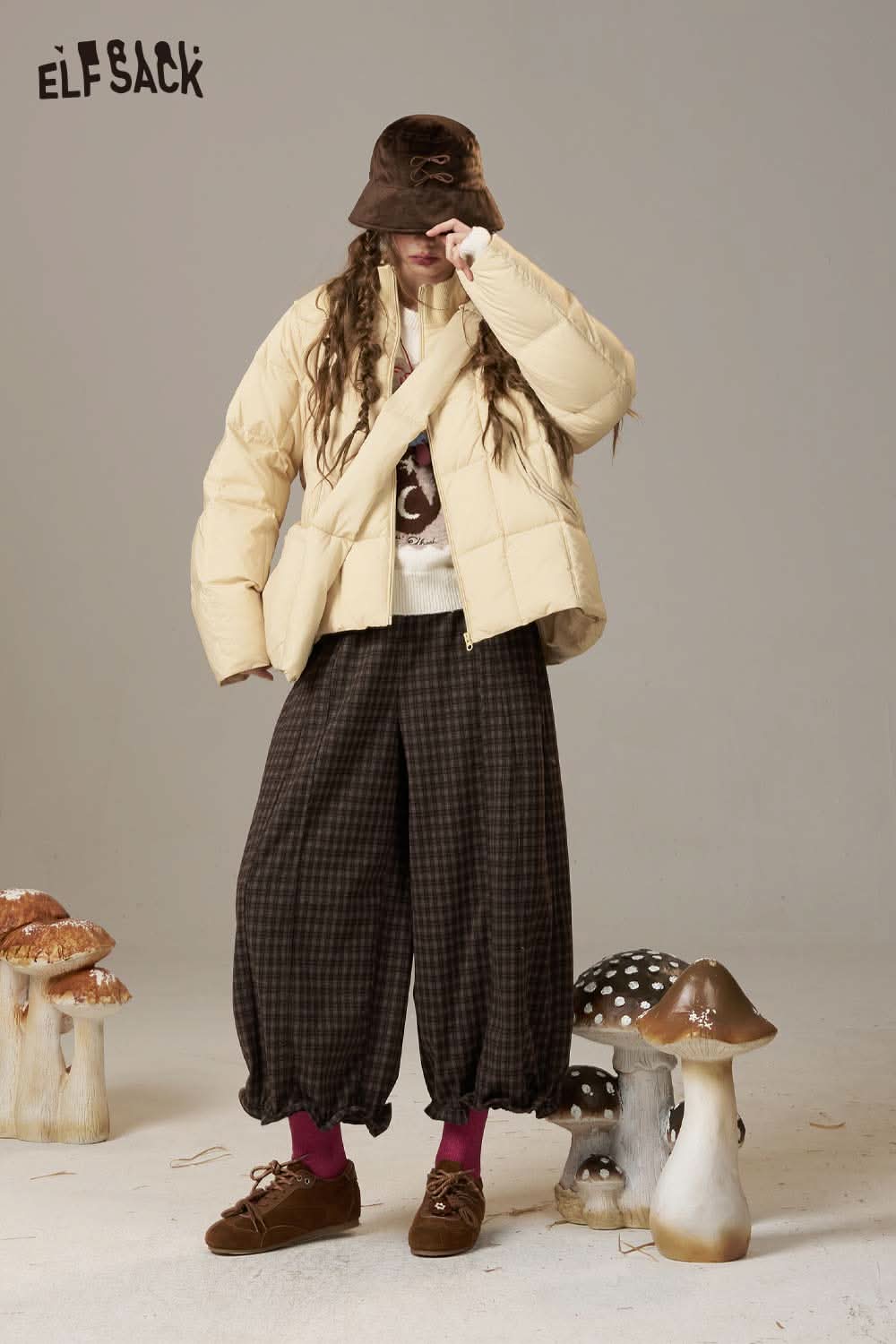Woman wearing an ELFSACK cartoon kitten embroidered sweater paired with stylish outerwear and baggy pants