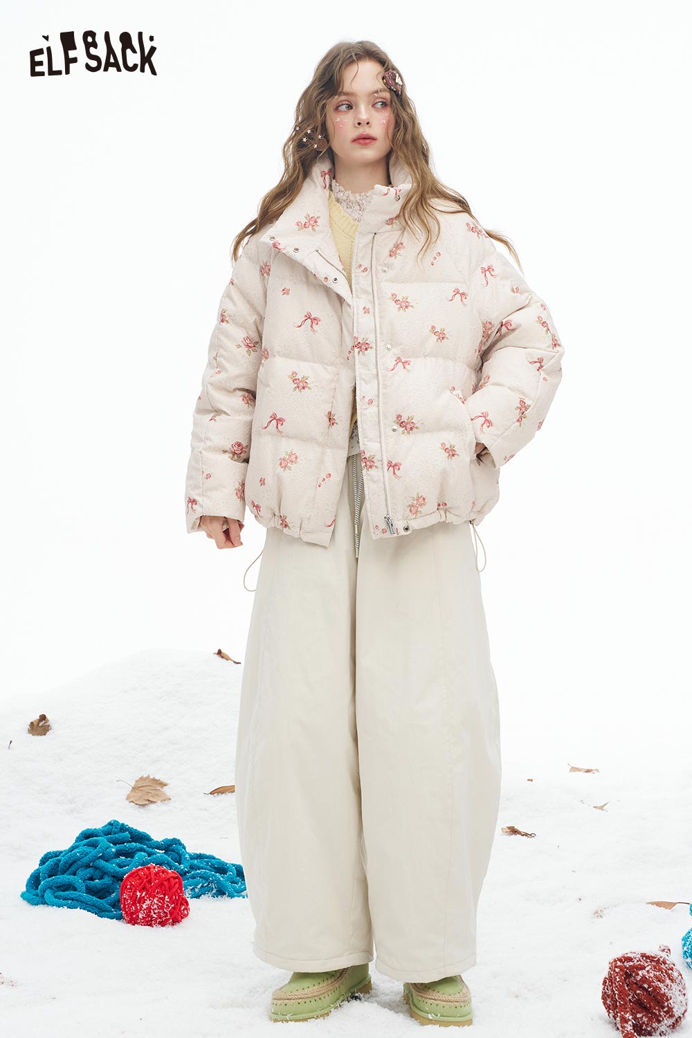 ELFSACK cute knit embroidered sweater for women styled with a puffy jacket and wide-leg pants in a snowy setting