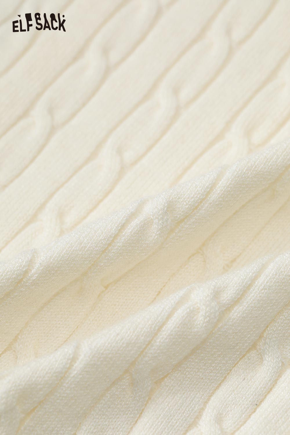 Close-up of ELFSACK minimalist slim fit knit top in creamy white featuring a subtle cable knit texture