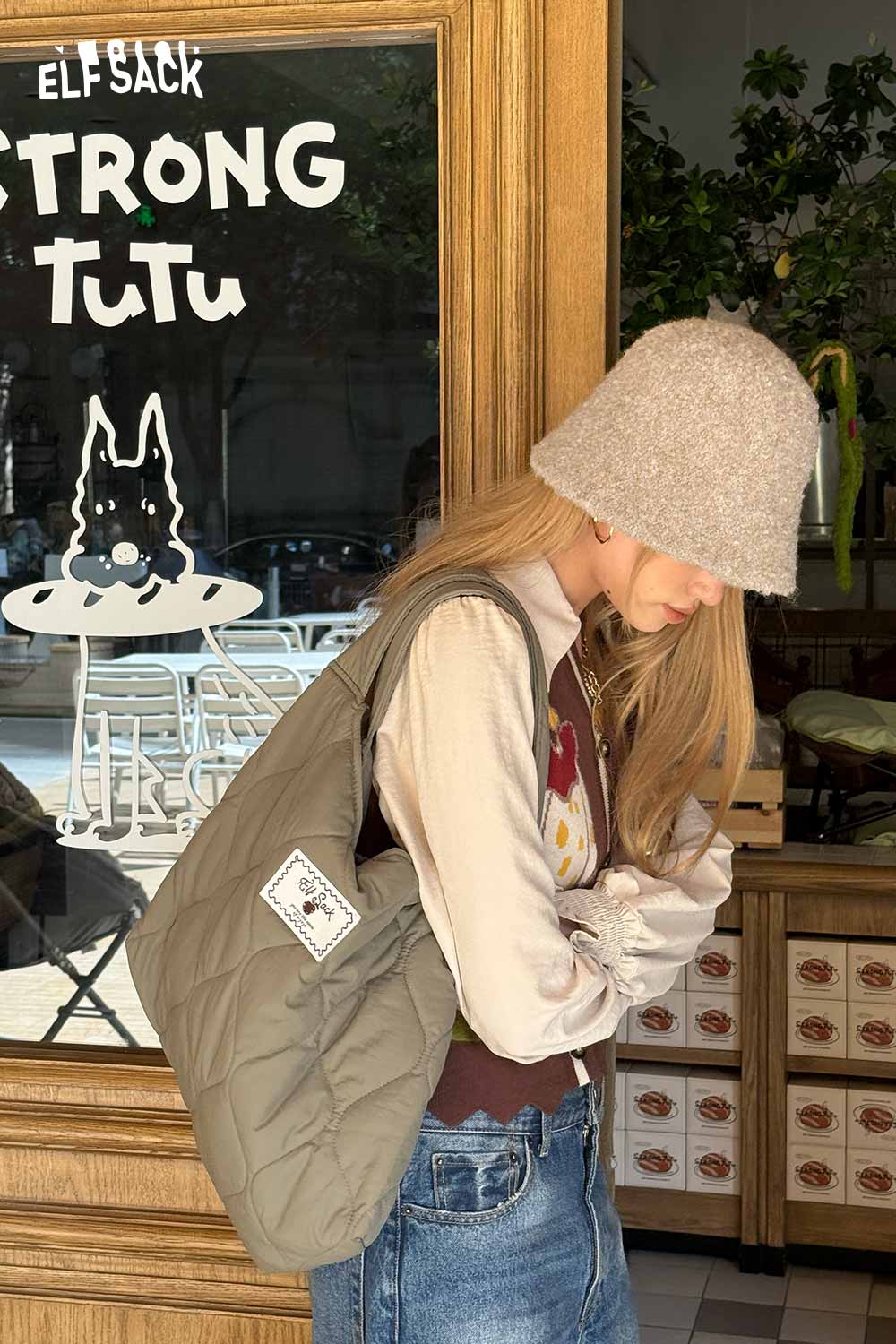 ELFSACK soft wool knit bucket hat featured on a model with a casual outfit in a cozy café