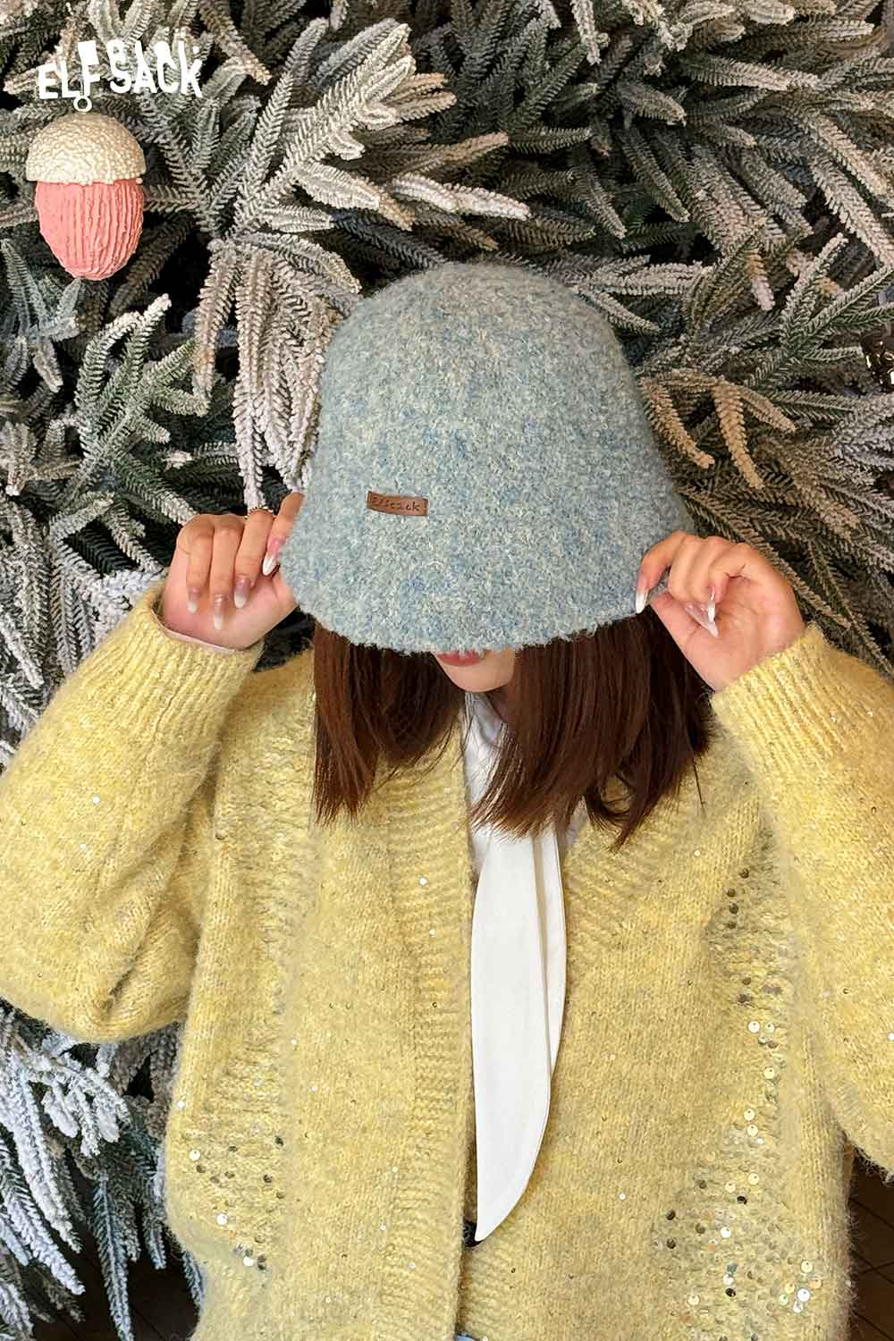 ELFSACK soft wool knit bucket hat in blue, worn under cozy sweater against a frosty background