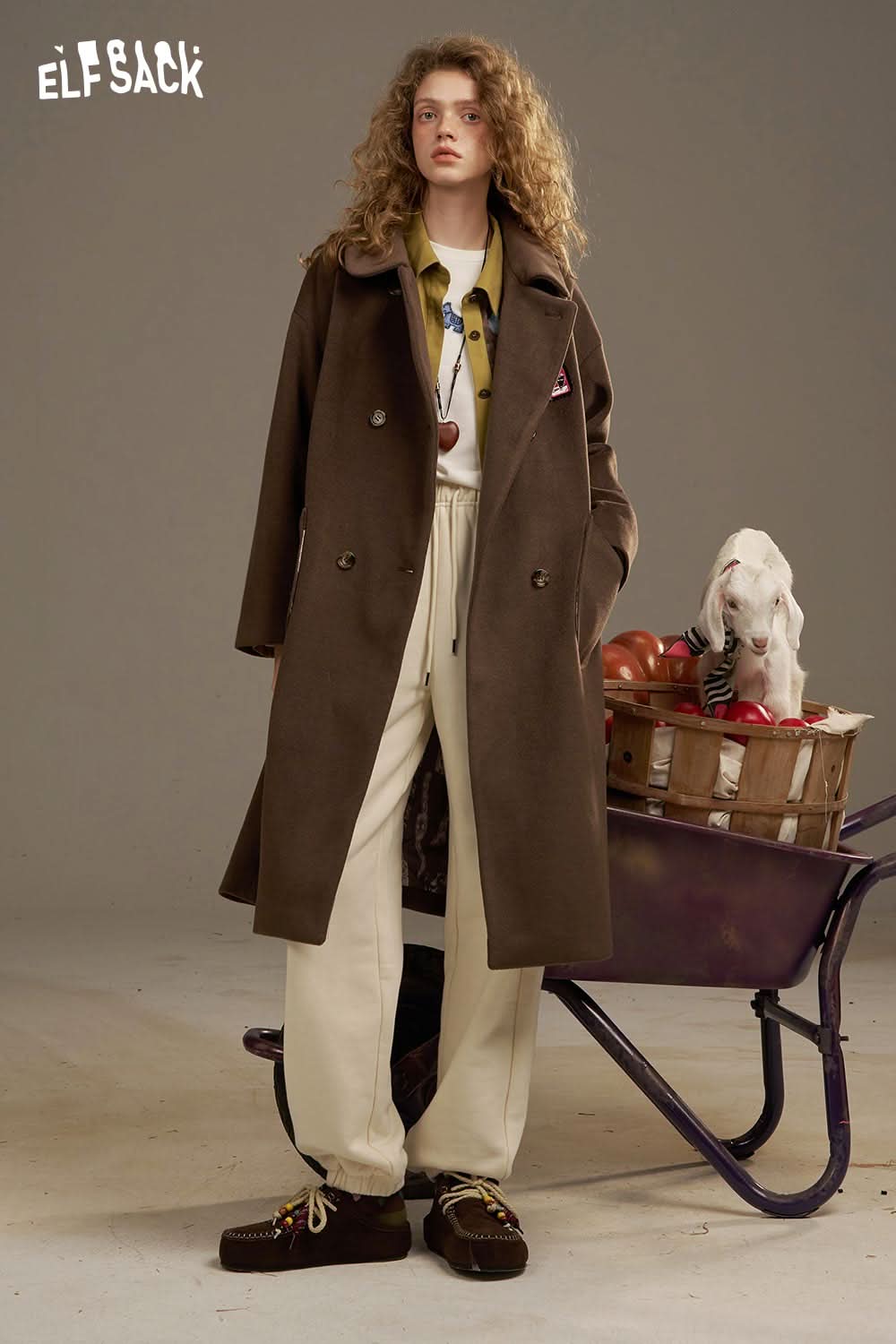ELFSACK model wearing white cropped sweat pants for women paired with a brown coat and stylish accessories