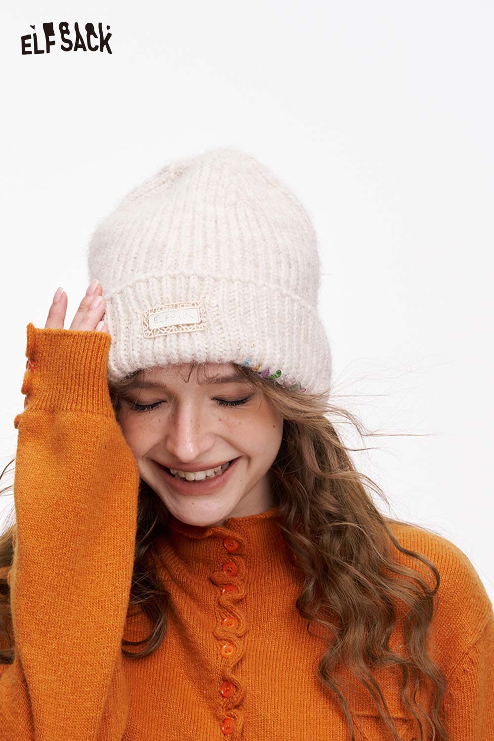 ELFSACK women's solid color beanie in cream paired with a cozy orange sweater for a stylish winter look