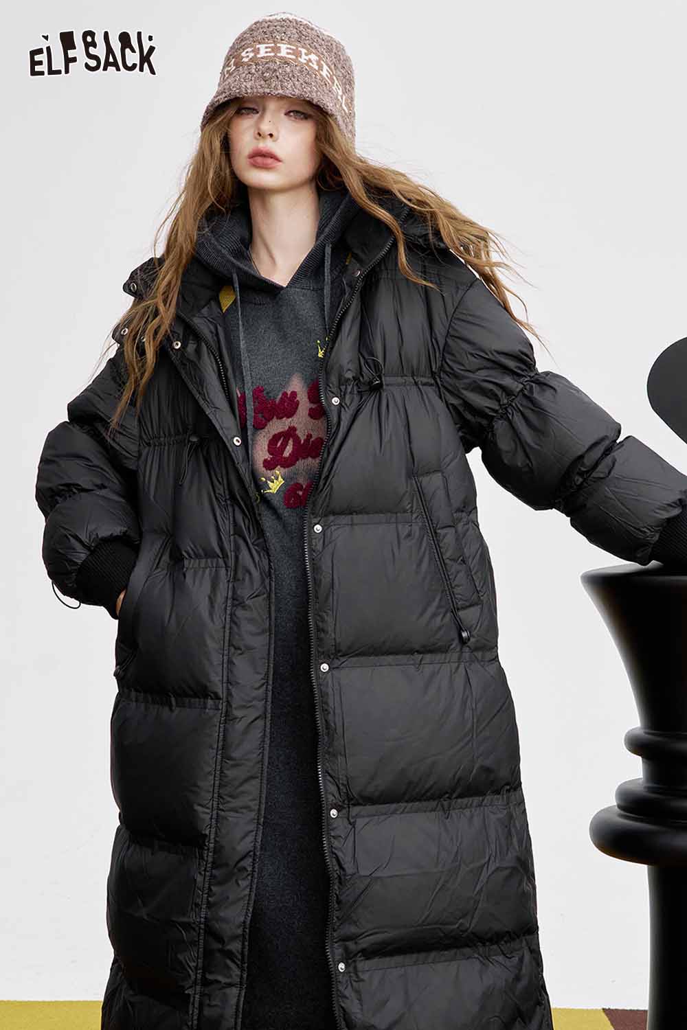 Stylish ELFSACK black puffer coat worn over an embroidered long dress for women in a chic outdoor setting