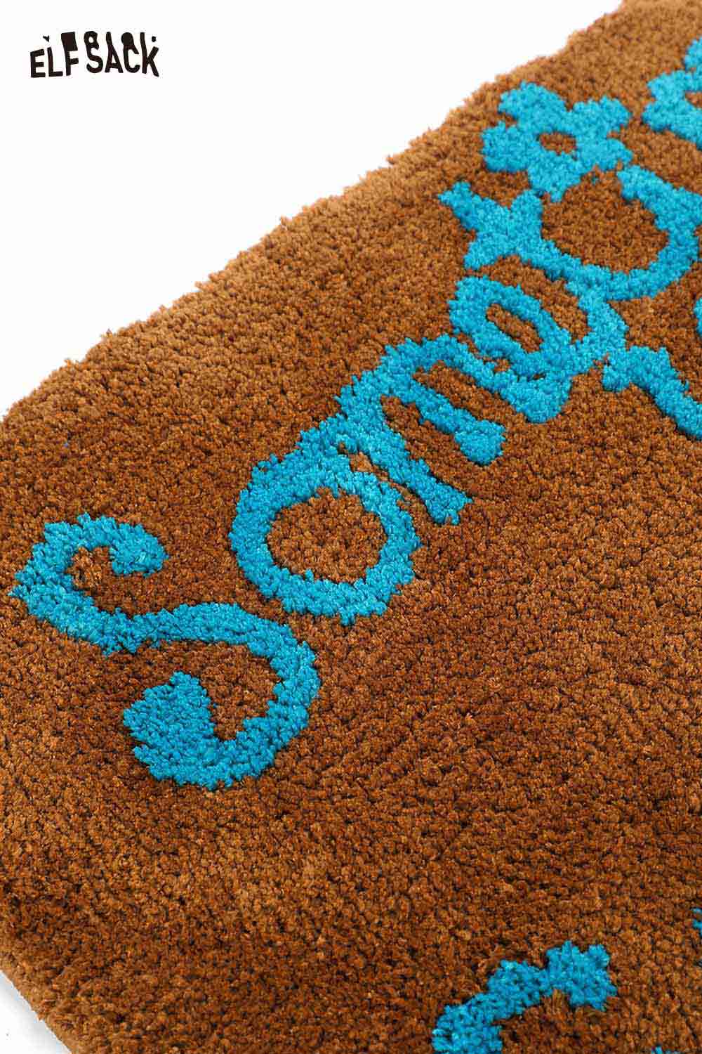 Felted wool rug with typography featuring vibrant blue text on a brown background