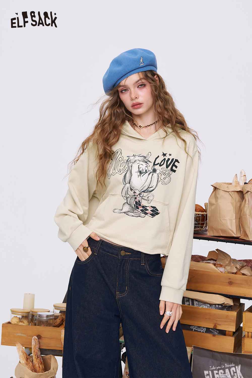 
                  
                    ELFSACK model wearing beige American style print hoodie for women with cartoon love graphic blue beret wide jeans
                  
                