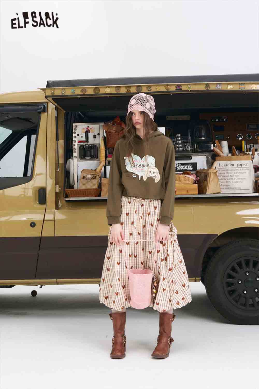 
                  
                    ELFSACK American style print hoodie for women olive graphic hoodie paired with patterned skirt boots and pink bag by food truck
                  
                