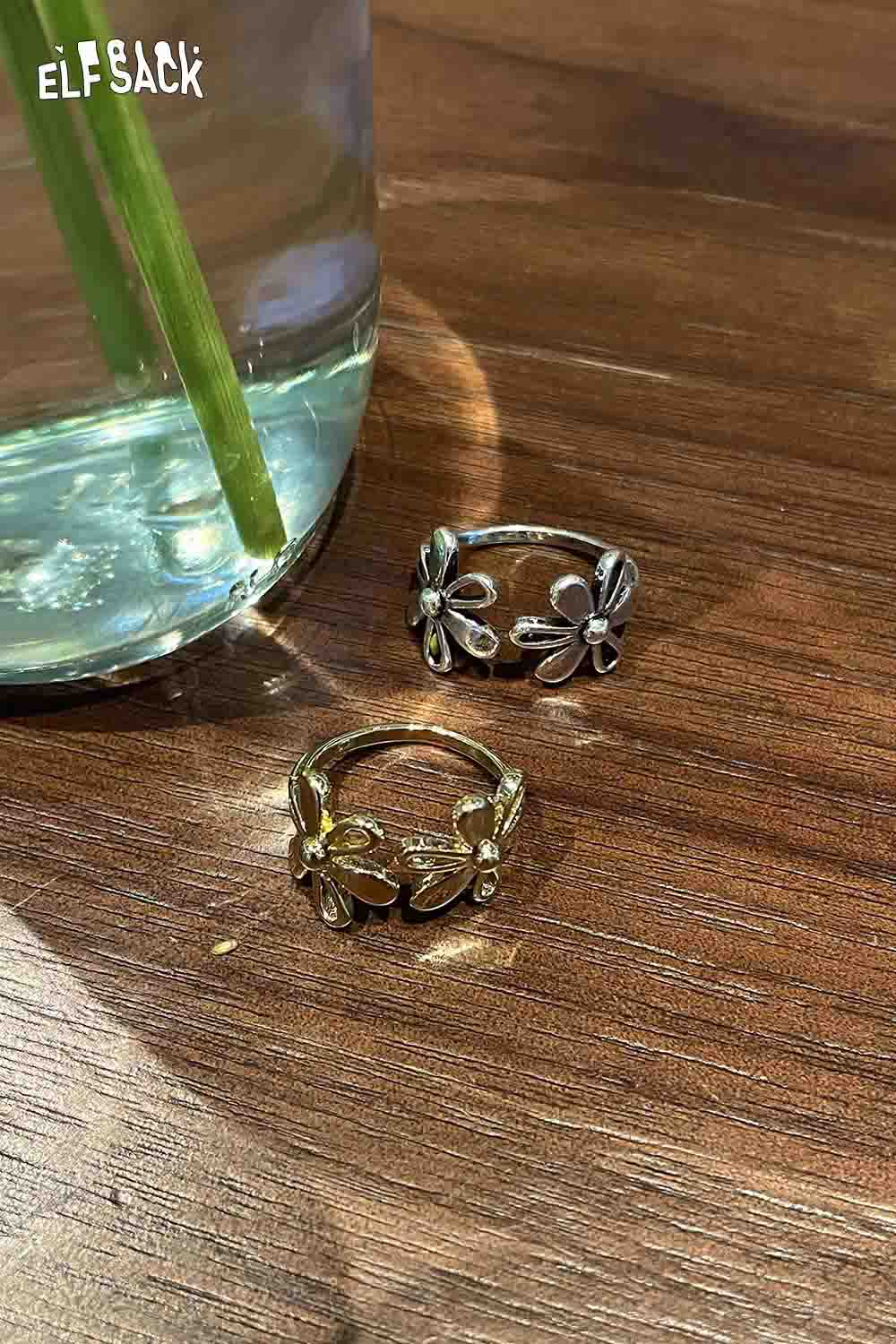 Floral copper statement ring in silver and gold styles displayed beside a glass vase with flowers