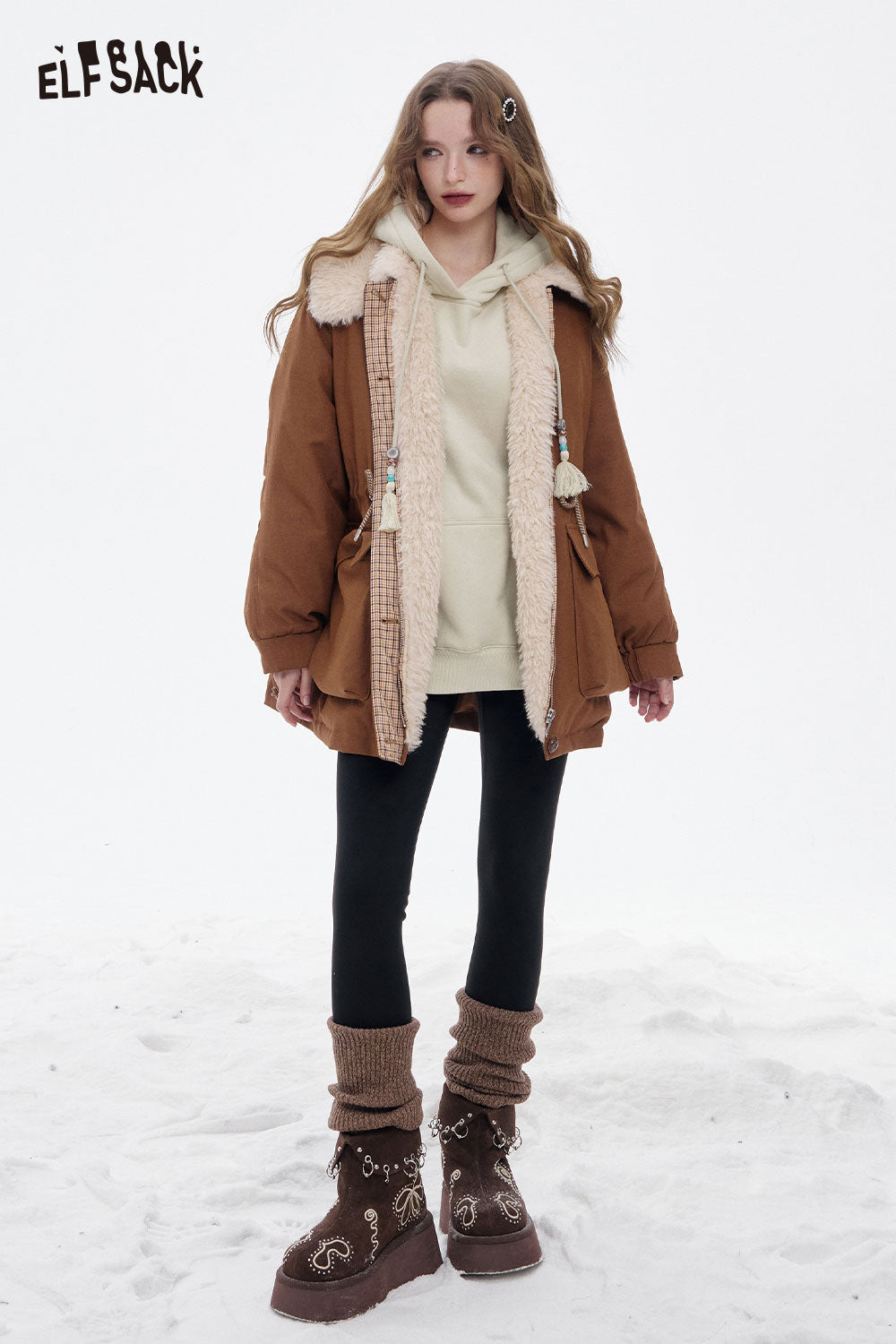 ELFSACK floral graphic tassel hoodie for women layered under a brown coat, paired with leggings and stylish boots