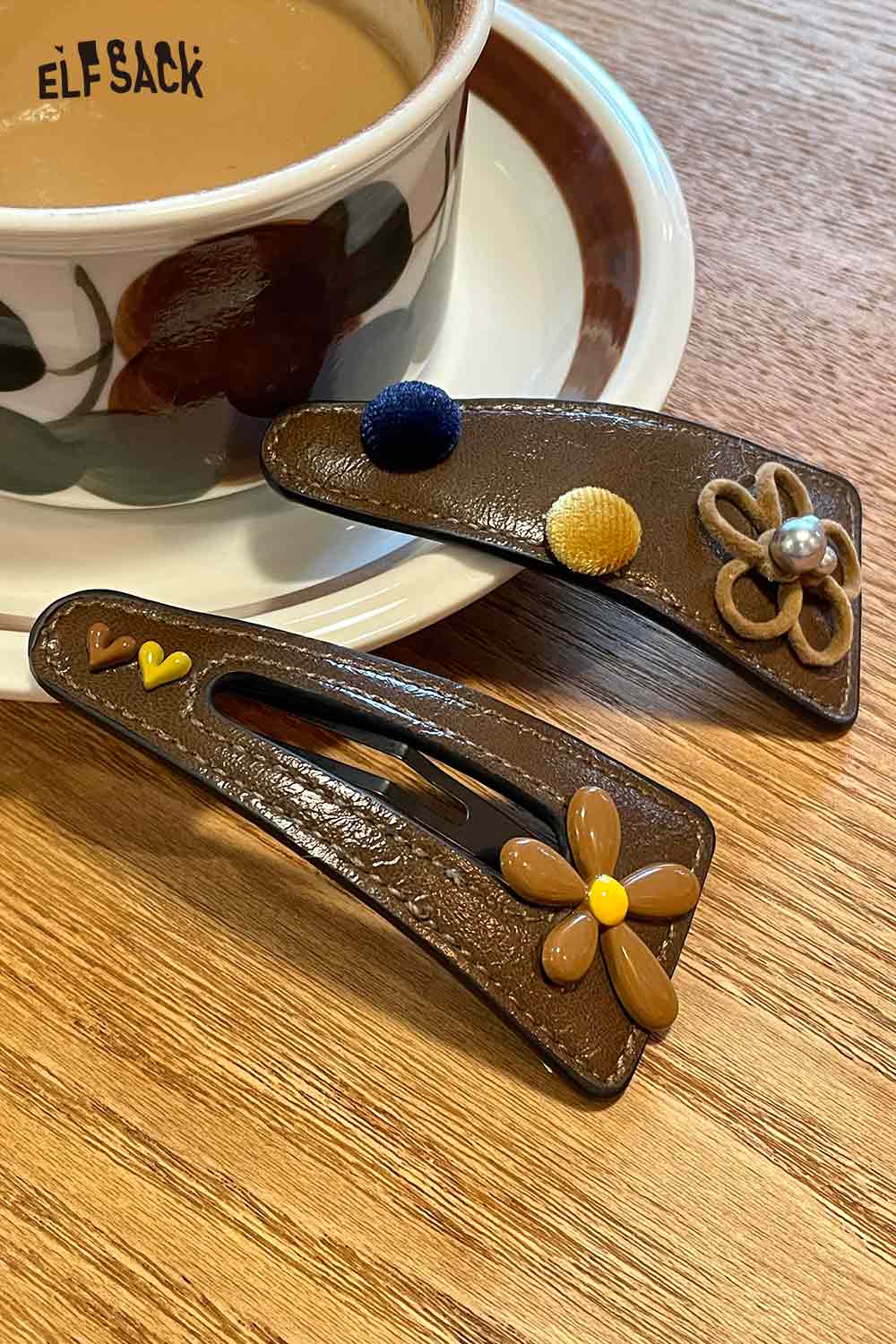 ELFSACK floral hair clip accessory with colorful embellishments on a wooden table with coffee