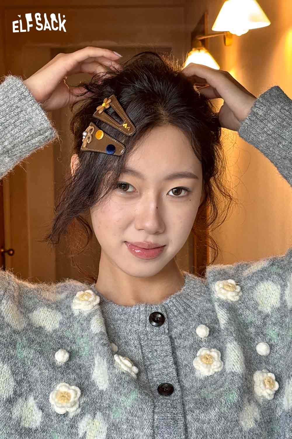 Model wearing a stylish floral hair clip accessory, paired with a cozy gray sweater