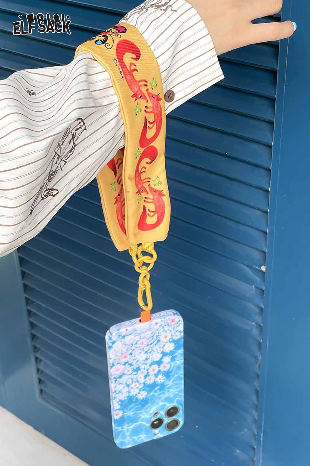 Colorful ELFSACK fox character phone strap attached to a floral phone case, perfect for stylish phone carrying.