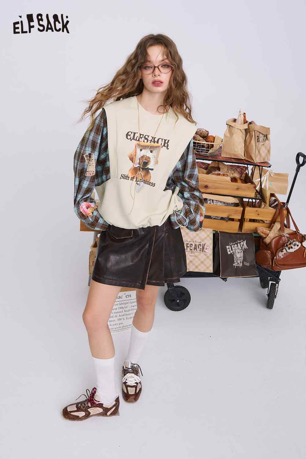 ELFSACK cream bread dog sweatshirt for women styled with plaid shirt leather skirt casual streetwear look