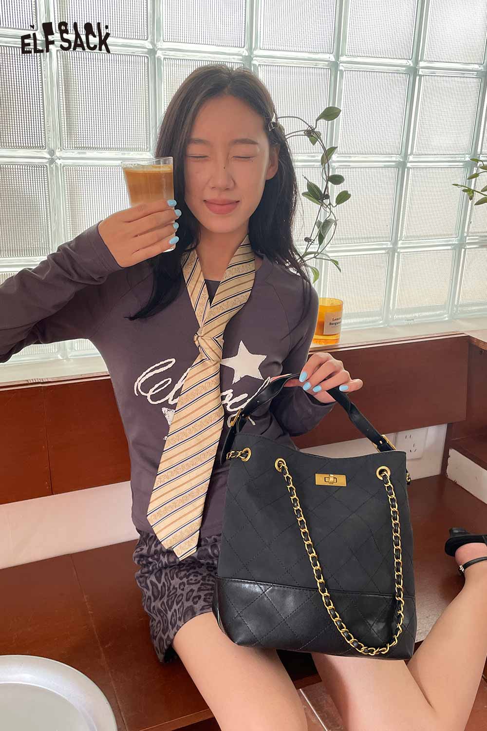 Model holding a drink while showcasing a genuine leather bucket bag from ELFSACK in a stylish setting