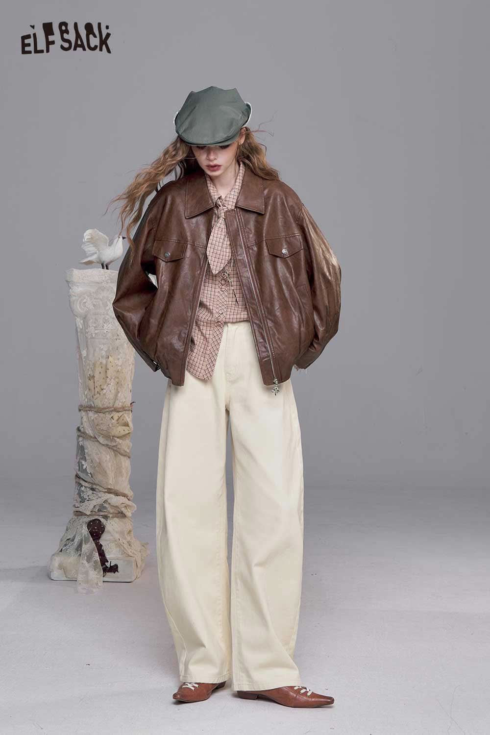 Model wearing heart embroidery white wide leg jeans paired with a brown leather jacket and hat