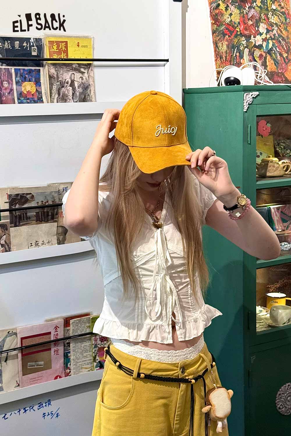 ELFSACK suede baseball cap in mustard yellow worn by a model in a stylish outfit
