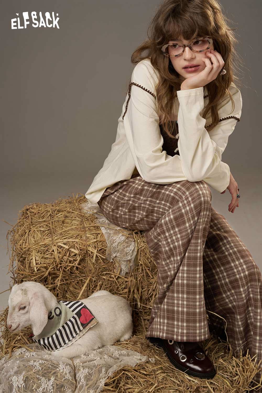 ELFSACK lace plaid straight leg pants styled casually with a model sitting beside a goat on bales of hay