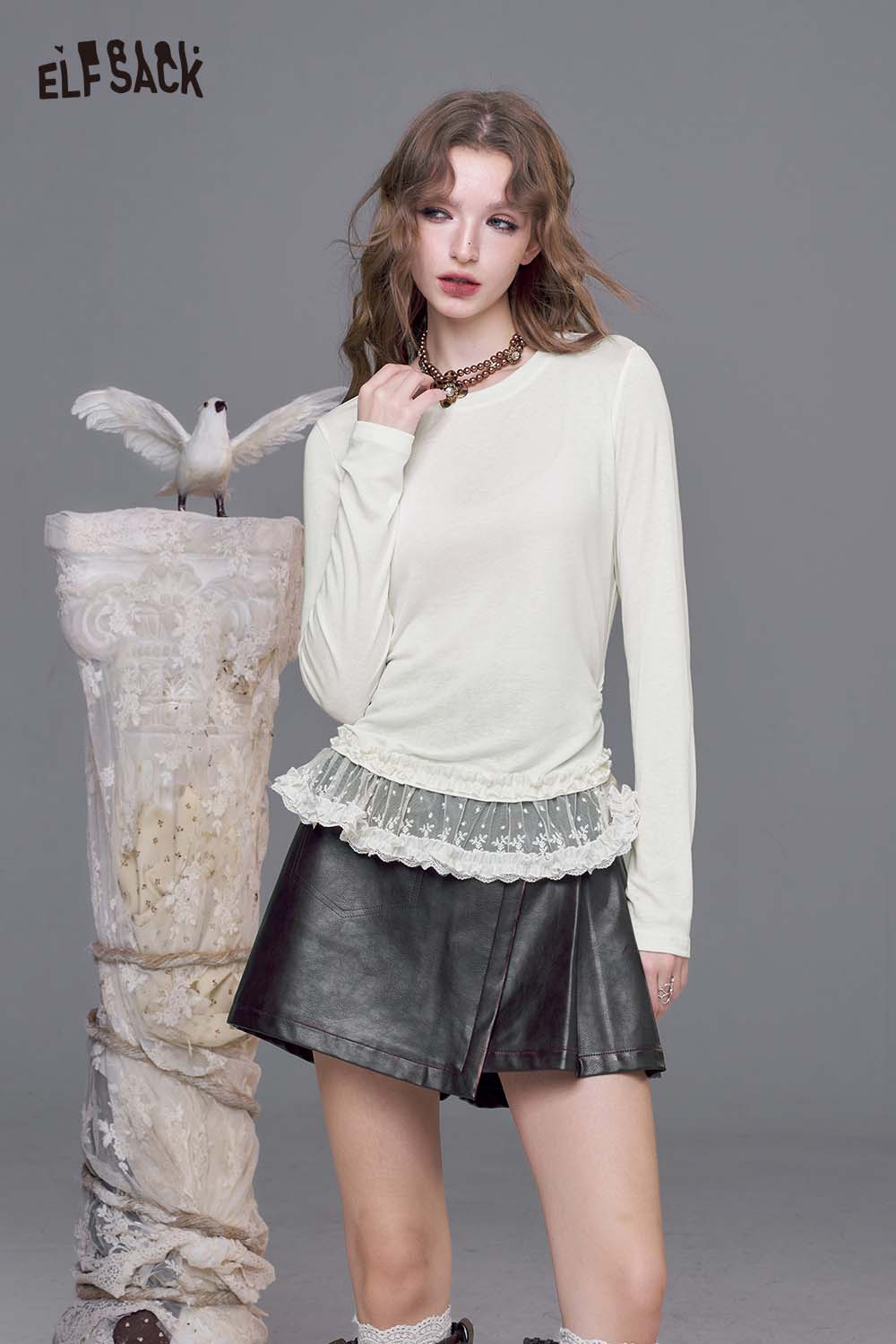 ELFSACK lace trim fitted tee for women in cream, styled with a layered lace hem and paired with a black skirt