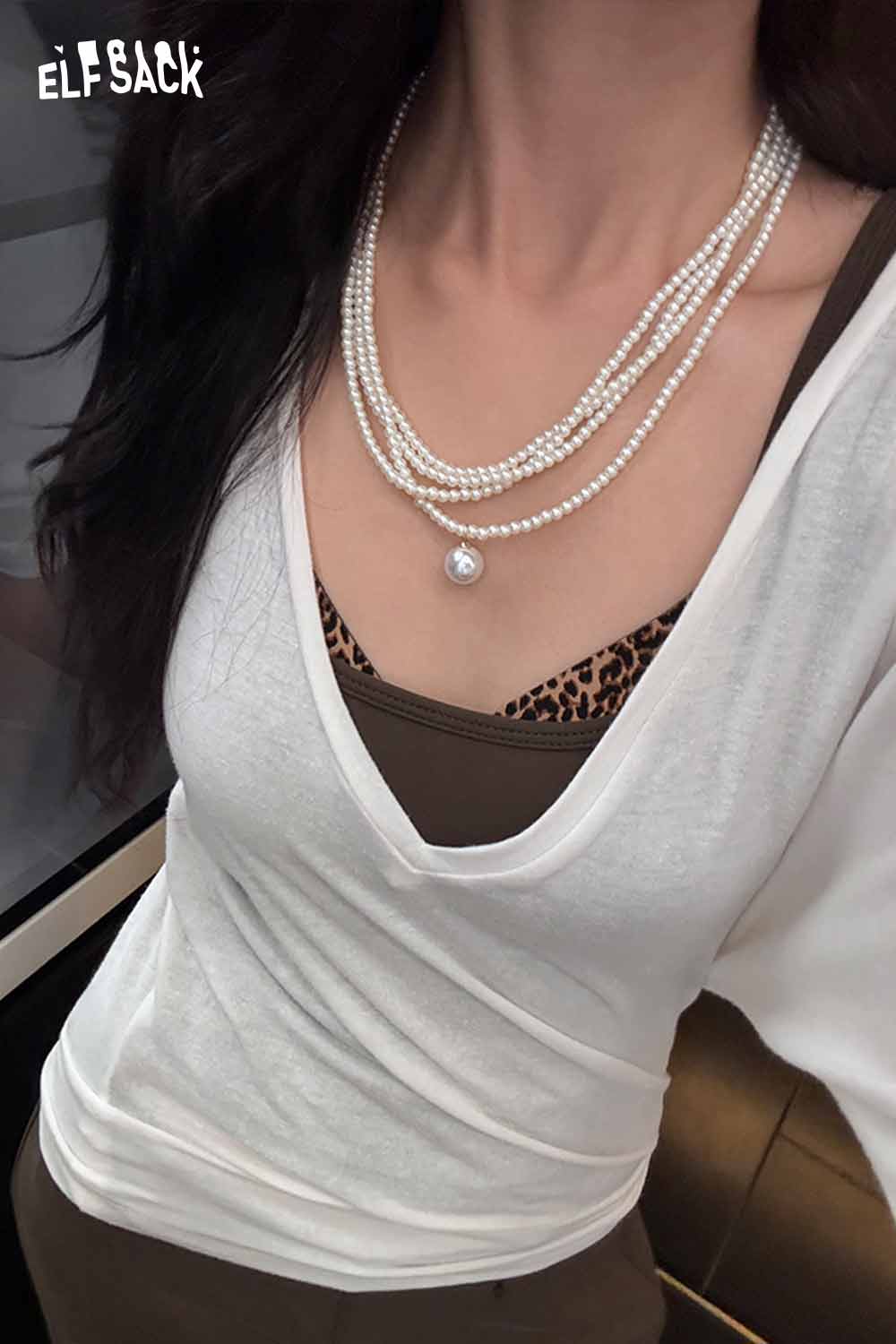 Stylish layered pearl choker necklace worn with a trendy white top and brown layering underneath