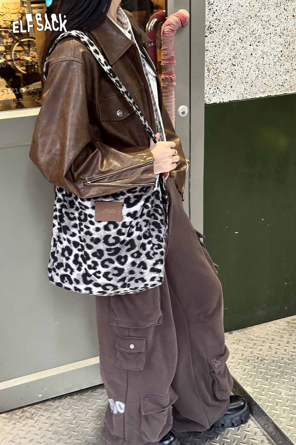 ELFSACK leopard print canvas tote bag displayed with stylish brown leather jacket and cargo pants