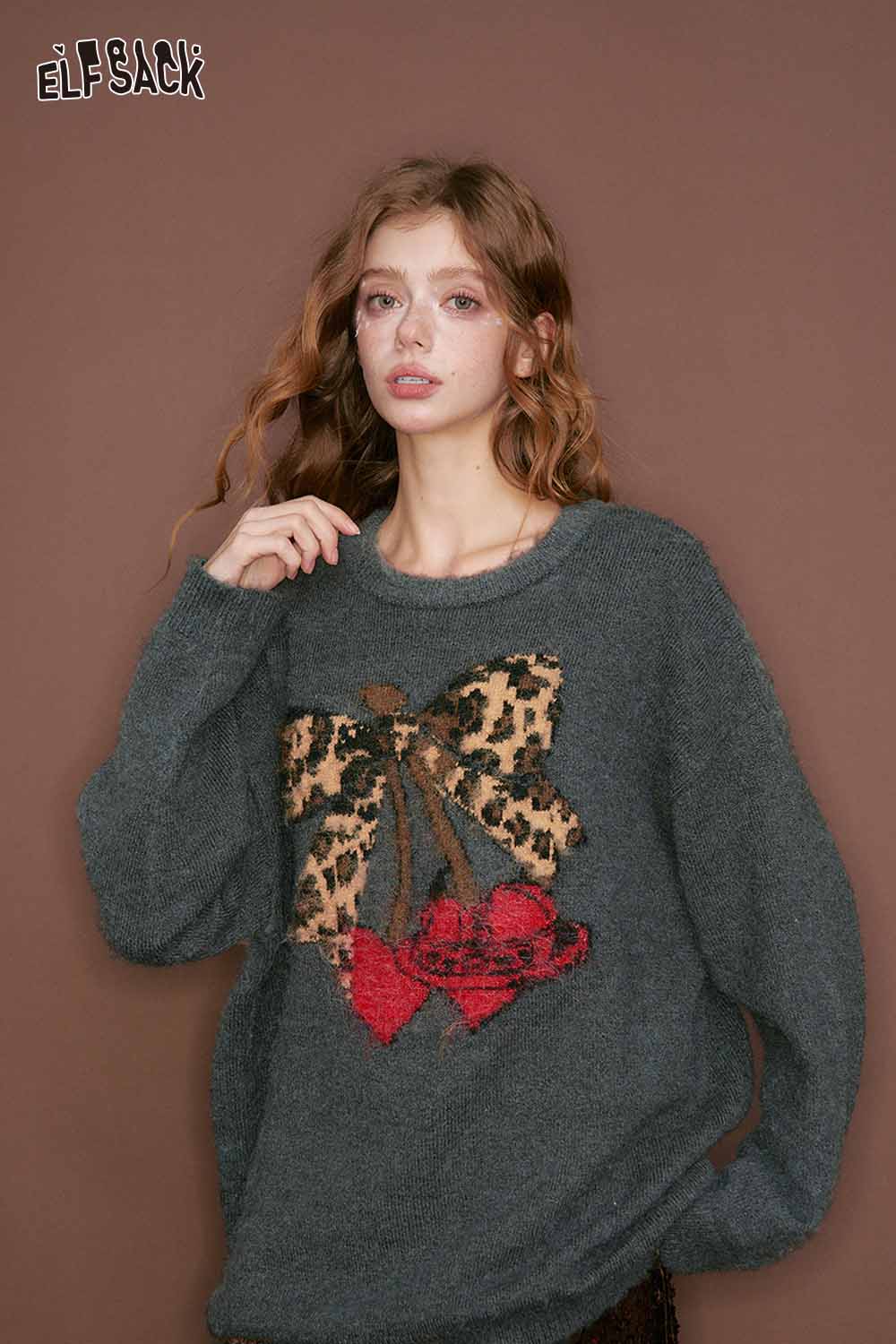 ELFSACK leopard print graphic sweater featuring a brown bow and red embellishments on a dark gray background