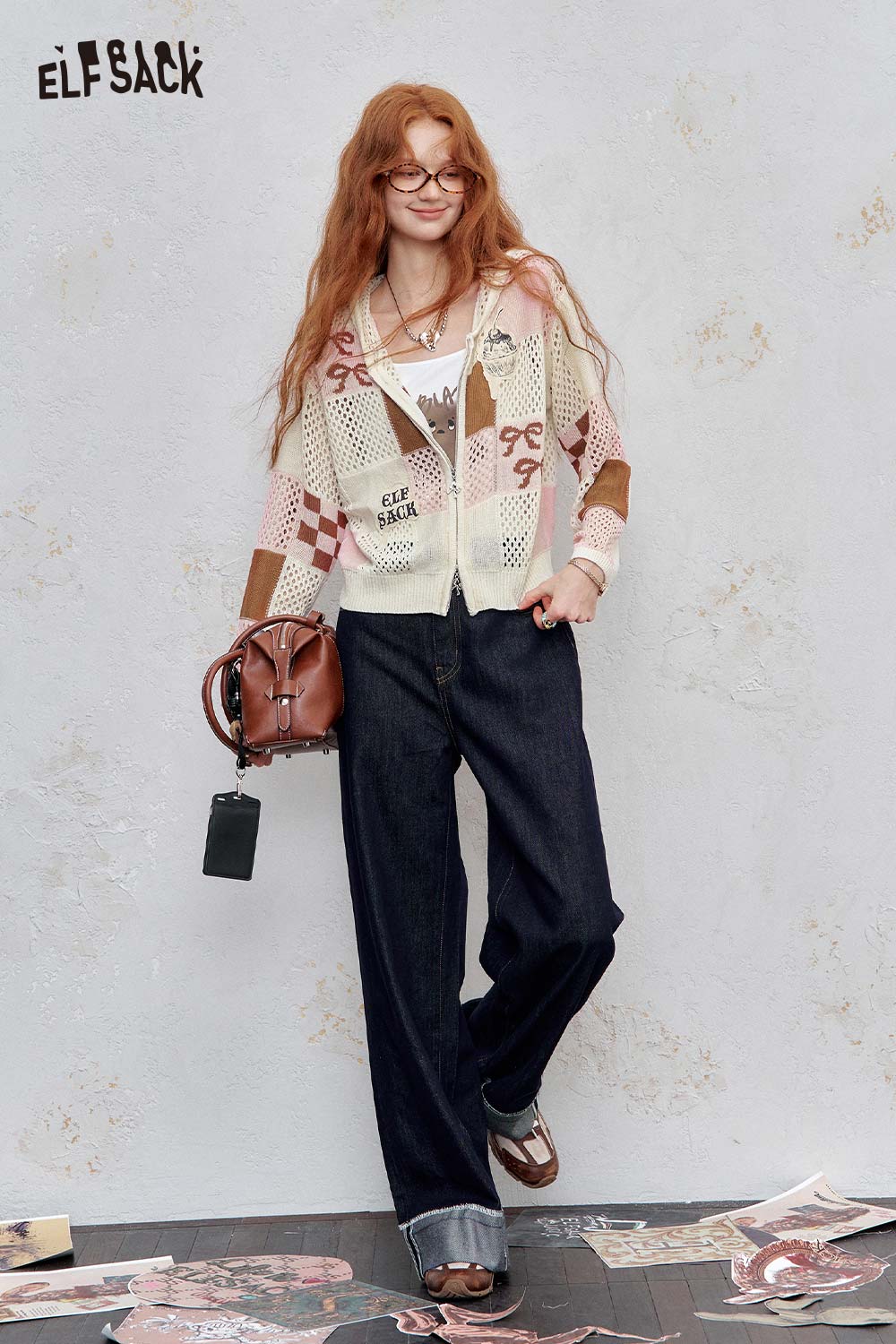 ELFSACK model wearing women's openwork knit zip hoodie in cream with geometric patterns paired with wide leg jeans