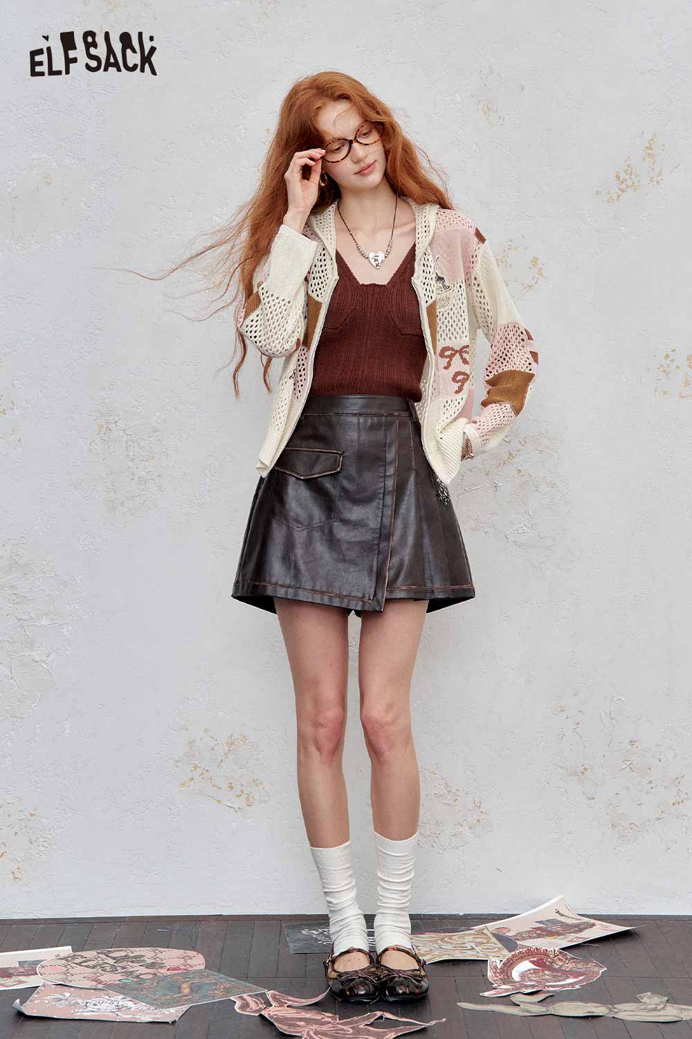 ELFSACK model wearing women's openwork knit zip hoodie cream pink over brown tank with leather mini skirt
