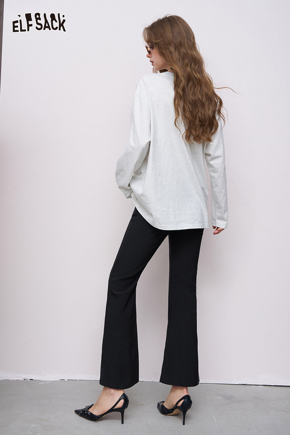 ELFSACK women's ankle-length flared pants in black shown from back paired with white top and heels