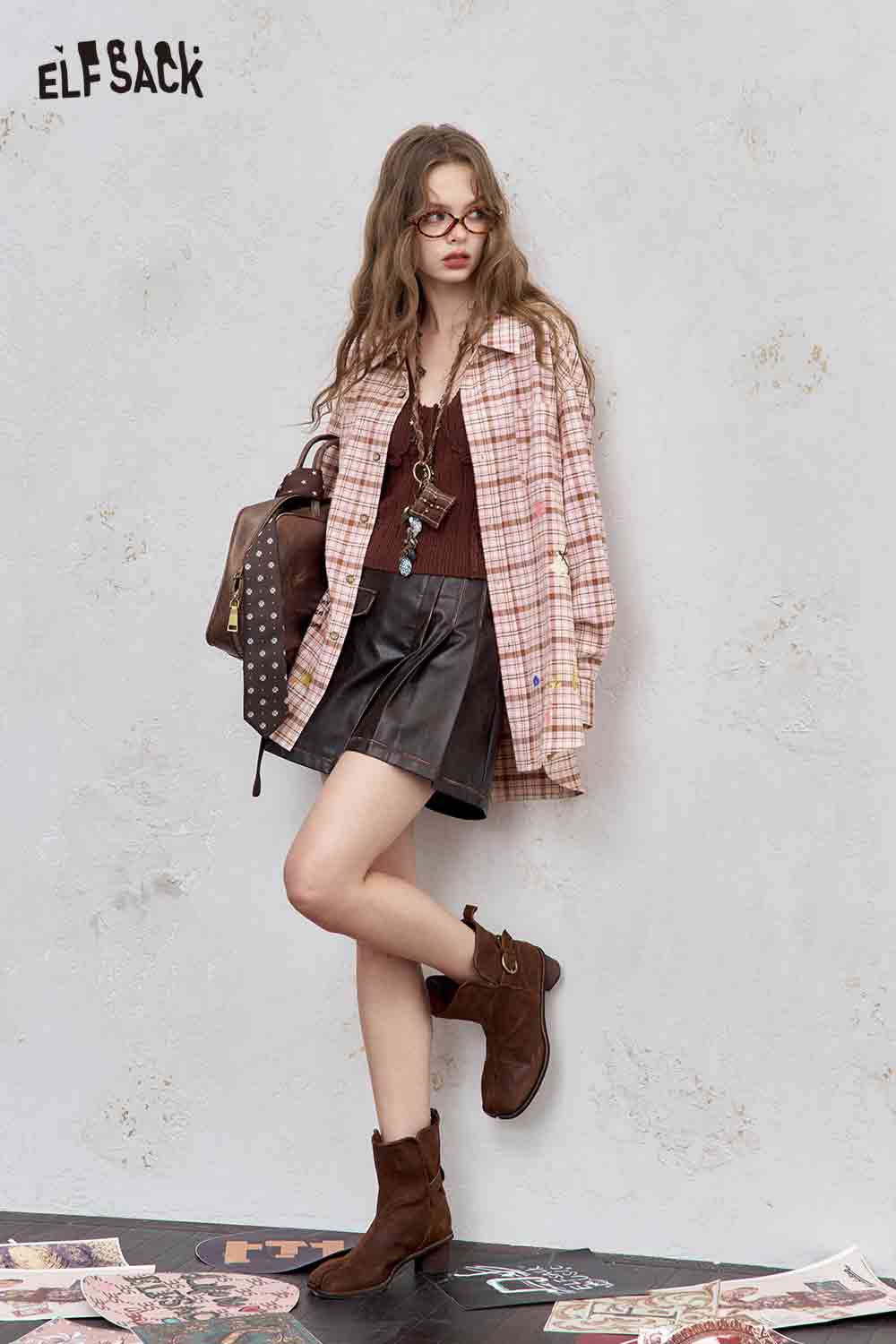 Model wearing college style plaid shirt for women in pink oversized plaid with brown top and suede boots