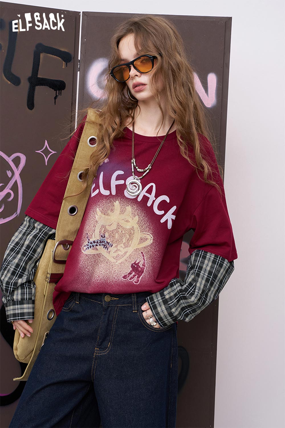 ELFSACK model wearing a burgundy luminous strawberry embroidered tee with layered plaid sleeves