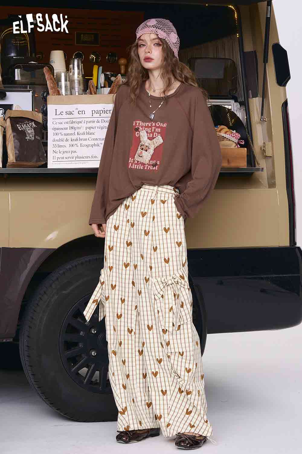 Model wearing ELFSACK heart plaid wide-leg pants in cream with gold hearts, side ties and oversized brown top