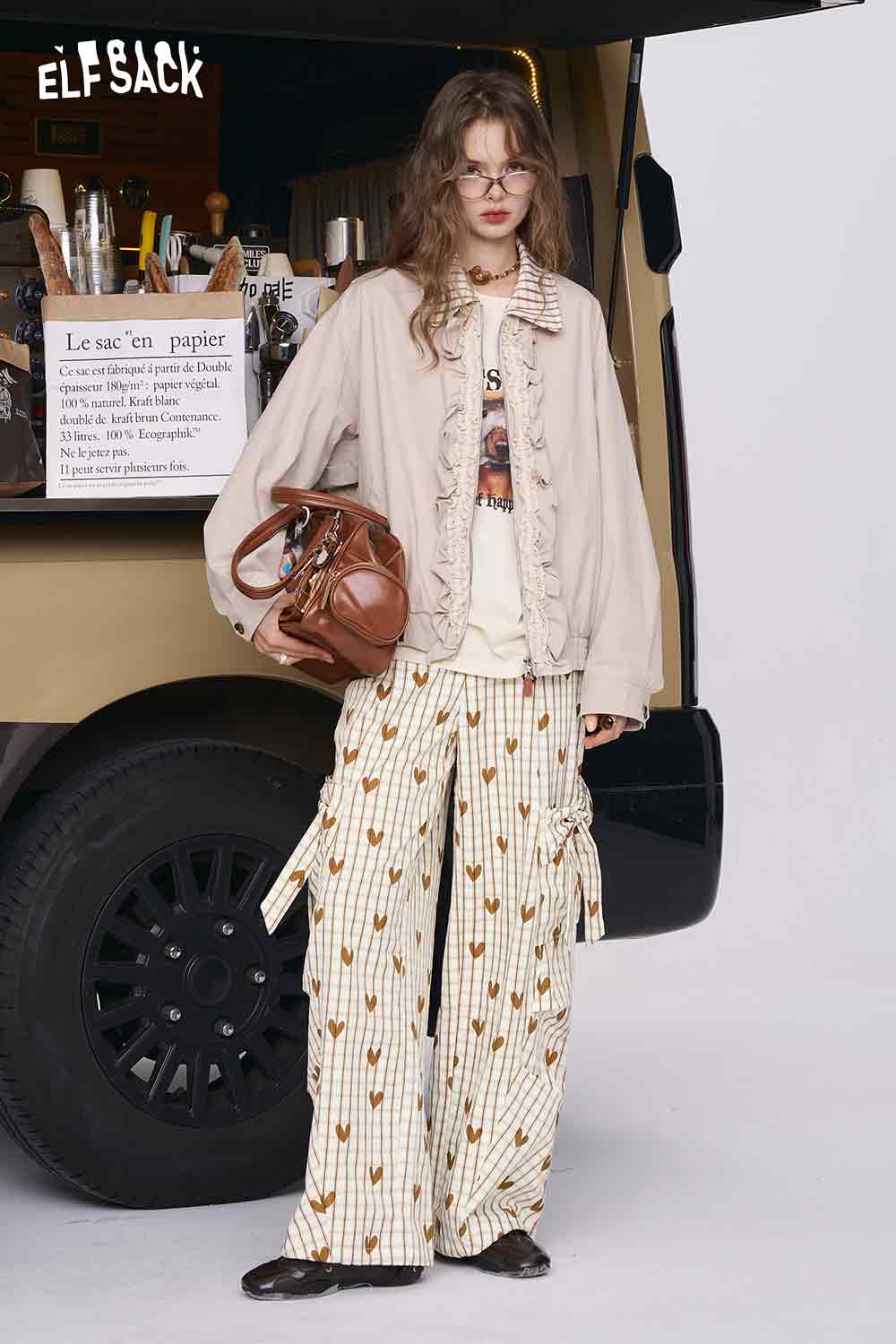 ELFSACK model wearing heart plaid wide-leg pants with cream stripes and tan heart print paired with beige jacket
