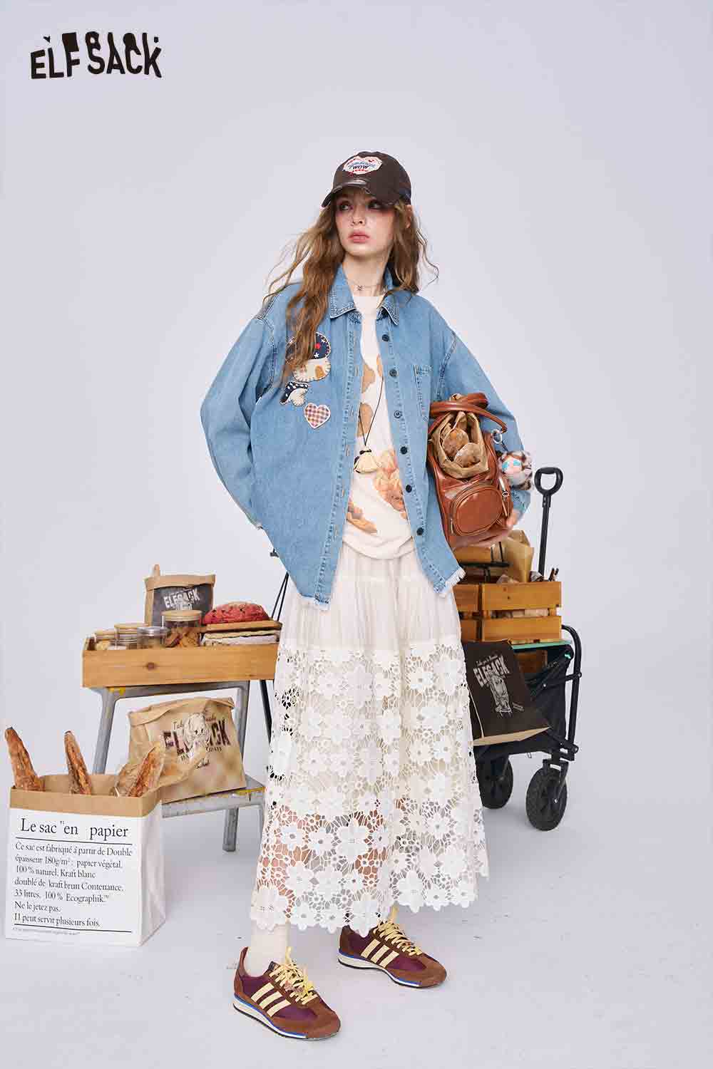 ELFSACK model wearing 3D mushroom denim shirt for women. Oversized patched denim jacket styled with lace maxi skirt and sneakers
