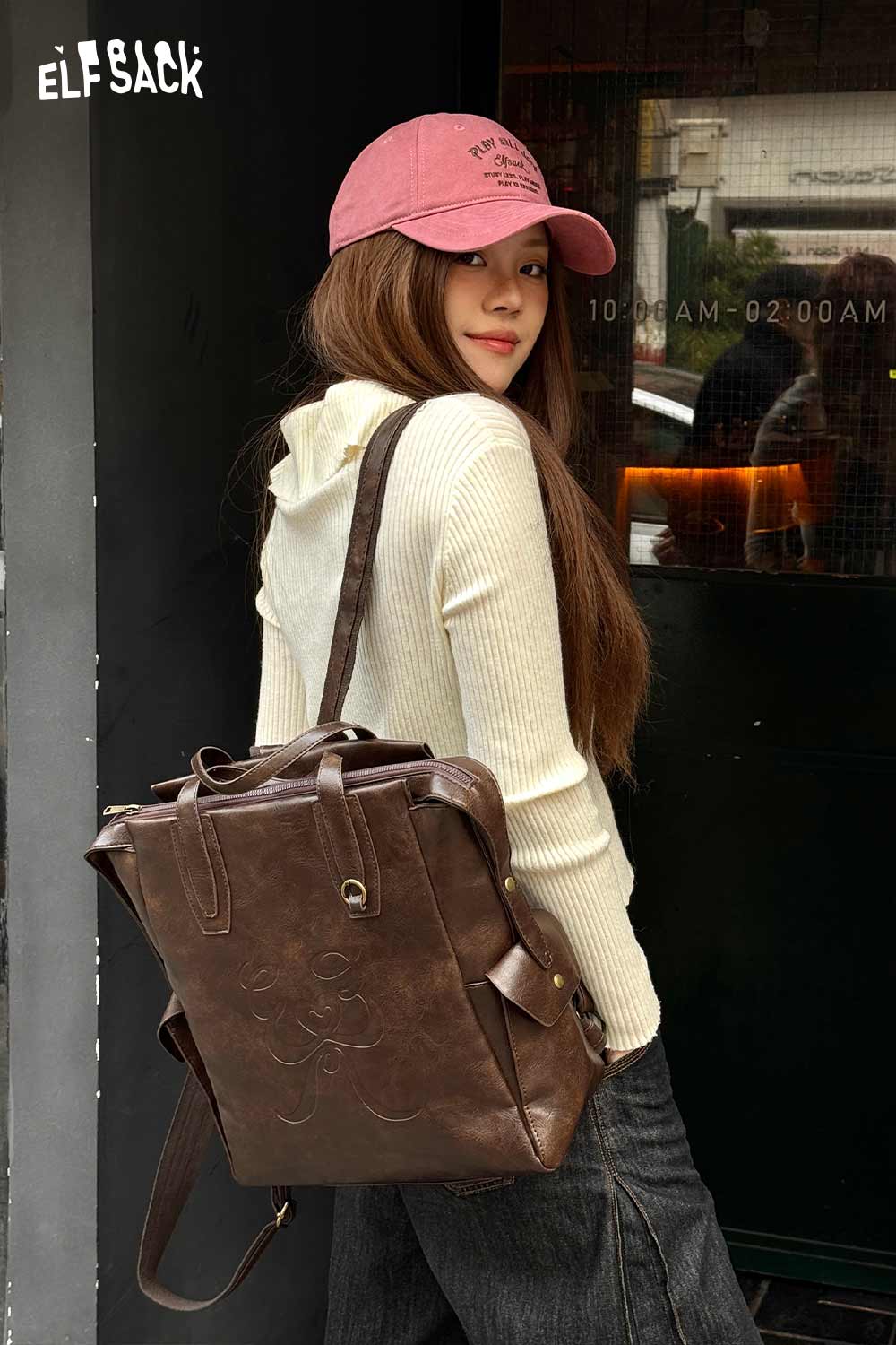 Stylish woman wearing a minimalist brown backpack for women with a casual outfit and cap