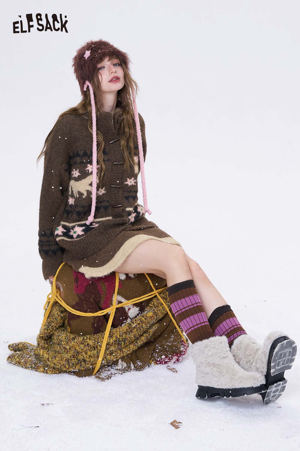 Model wearing a cozy outfit with a minimalist Christmas stripe dress and warm accessories in a snowy setting