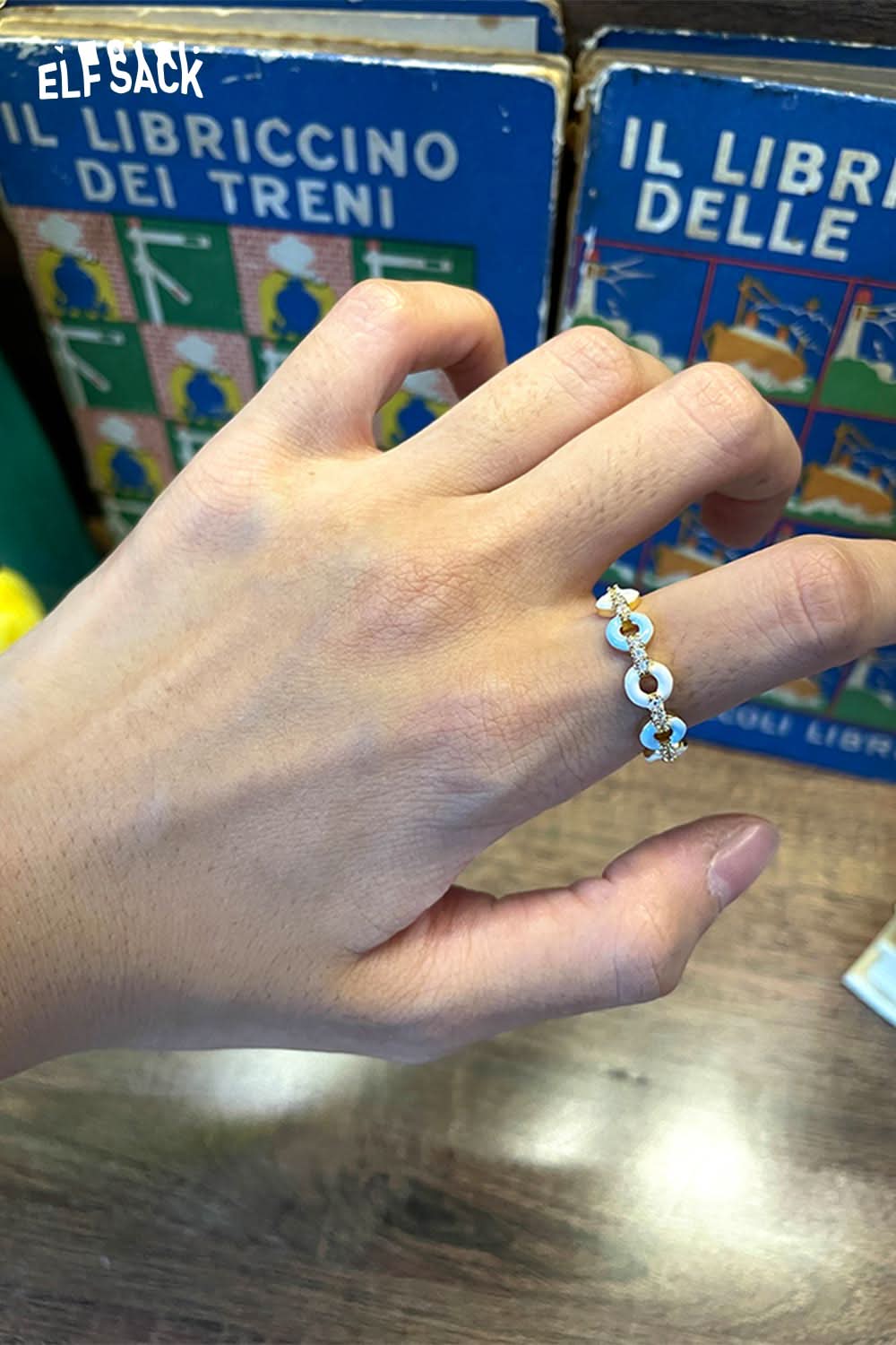 Elegant hand wearing a minimalist copper coin ring against vintage book background