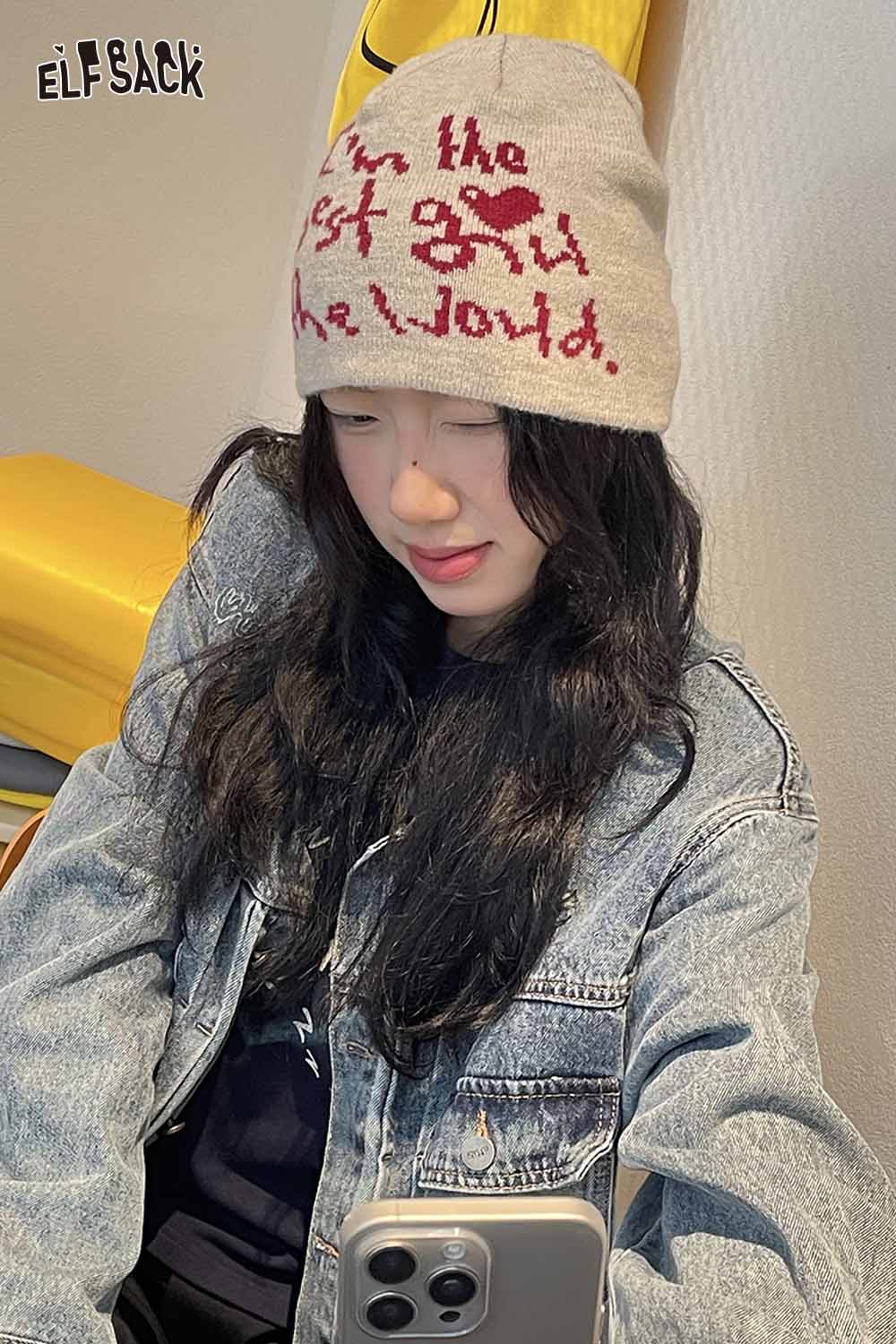 ELFSACK Minimalist letter graphic beanie in beige worn by a woman with black hair and denim jacket